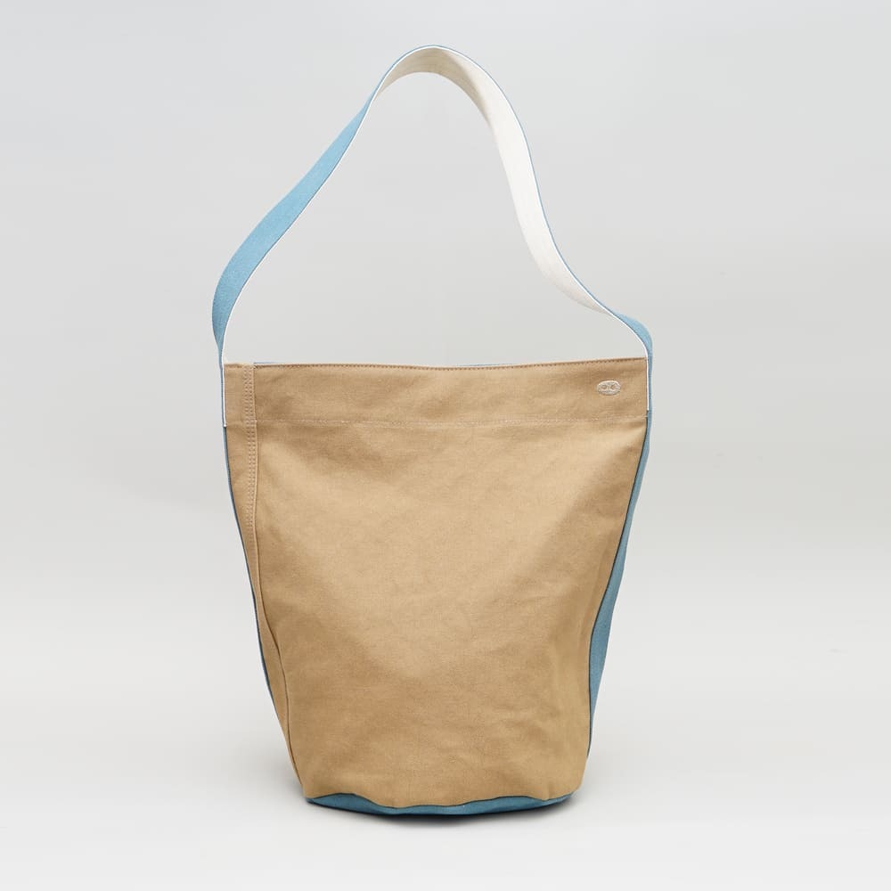 阿福圓筒帆布包正面展示，褐土色調與立體圓柱設計，適合日常與旅行使用