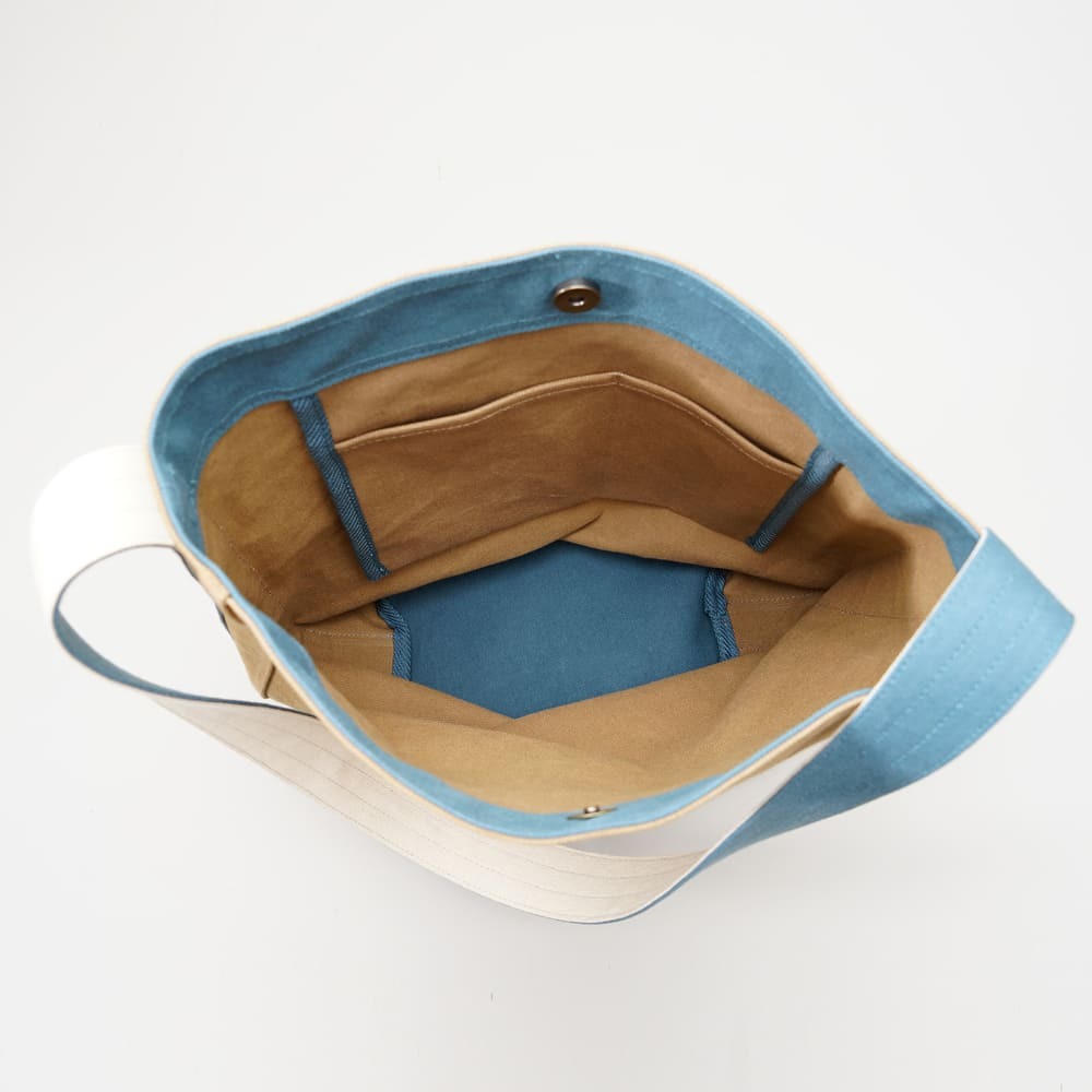 阿福圓筒帆布包正面展示，褐土色調與立體圓柱設計，適合日常與旅行使用