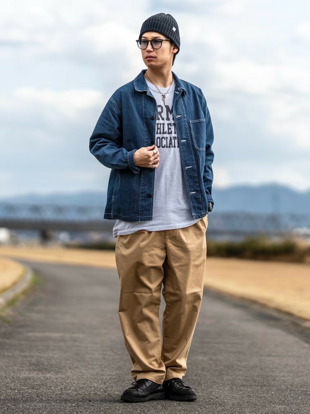 男生日系復古穿搭,配戴 Ray-Ban 黑色太陽眼鏡、EDJ SILVER 銀飾項鍊,頭戴 Ron Herman 黑色針織帽,搭配 UNIQLO 牛仔外套、URBAN RESEARCH DOORS 印花T-shirt、WEGO 卡其色休閒褲,腳踩 Danner 黑色靴款,展現隨性街頭風格。