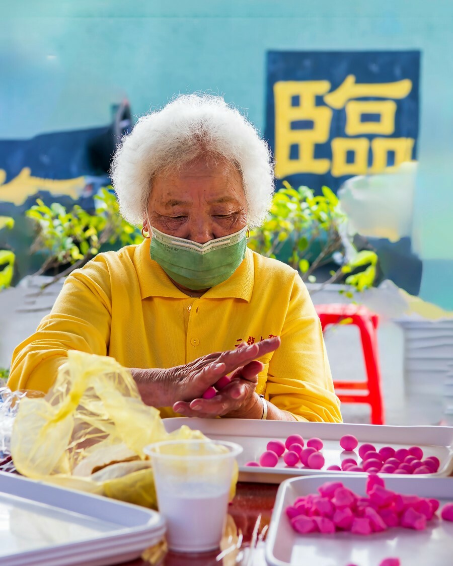 參加社區活動的老奶奶正在製作傳統湯圓,桌上擺滿粉紅糯米團
