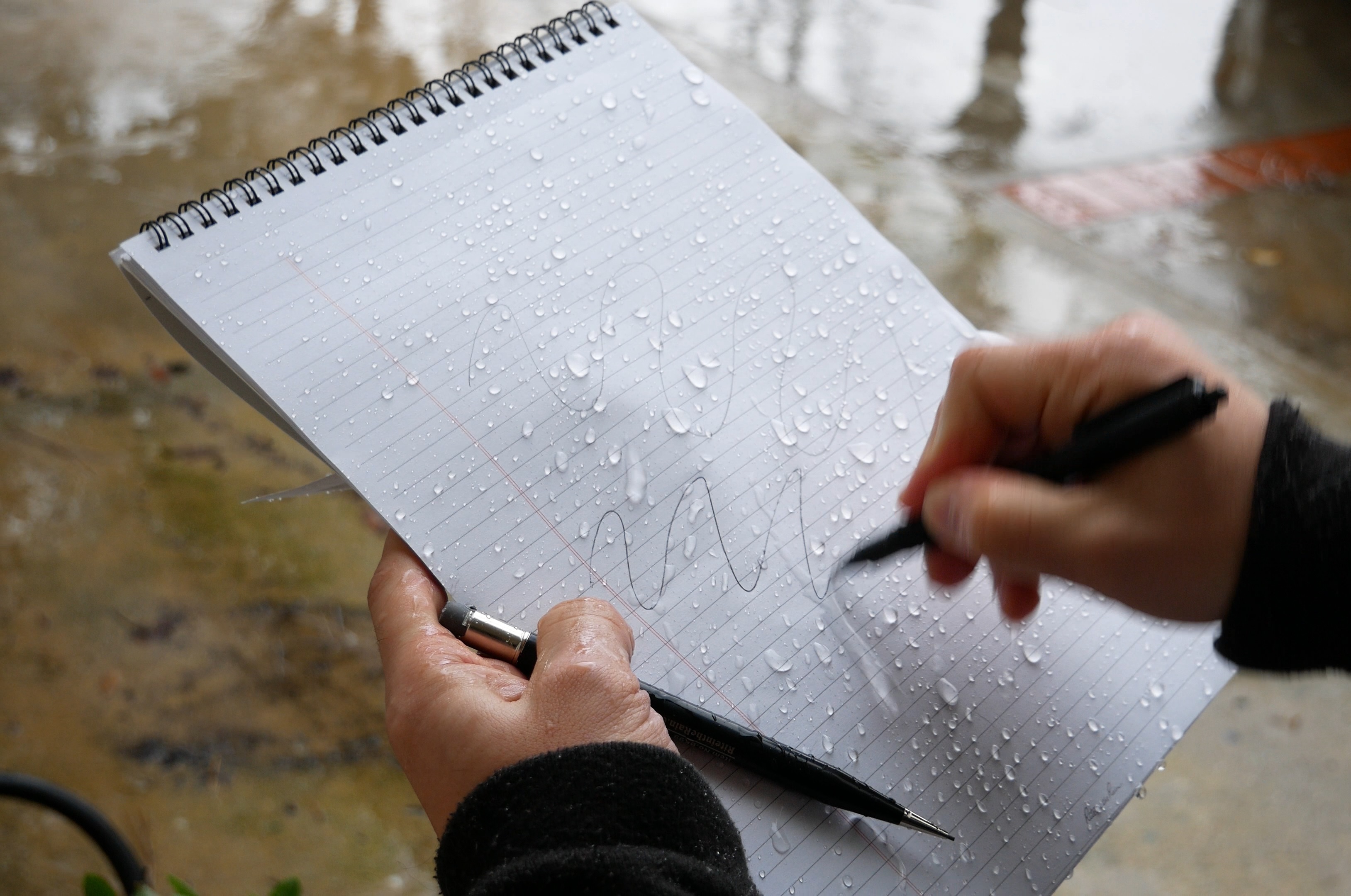 雨中手持 Rite in the Rain 筆記本書寫，紙帶仍保持乾淨清晰
