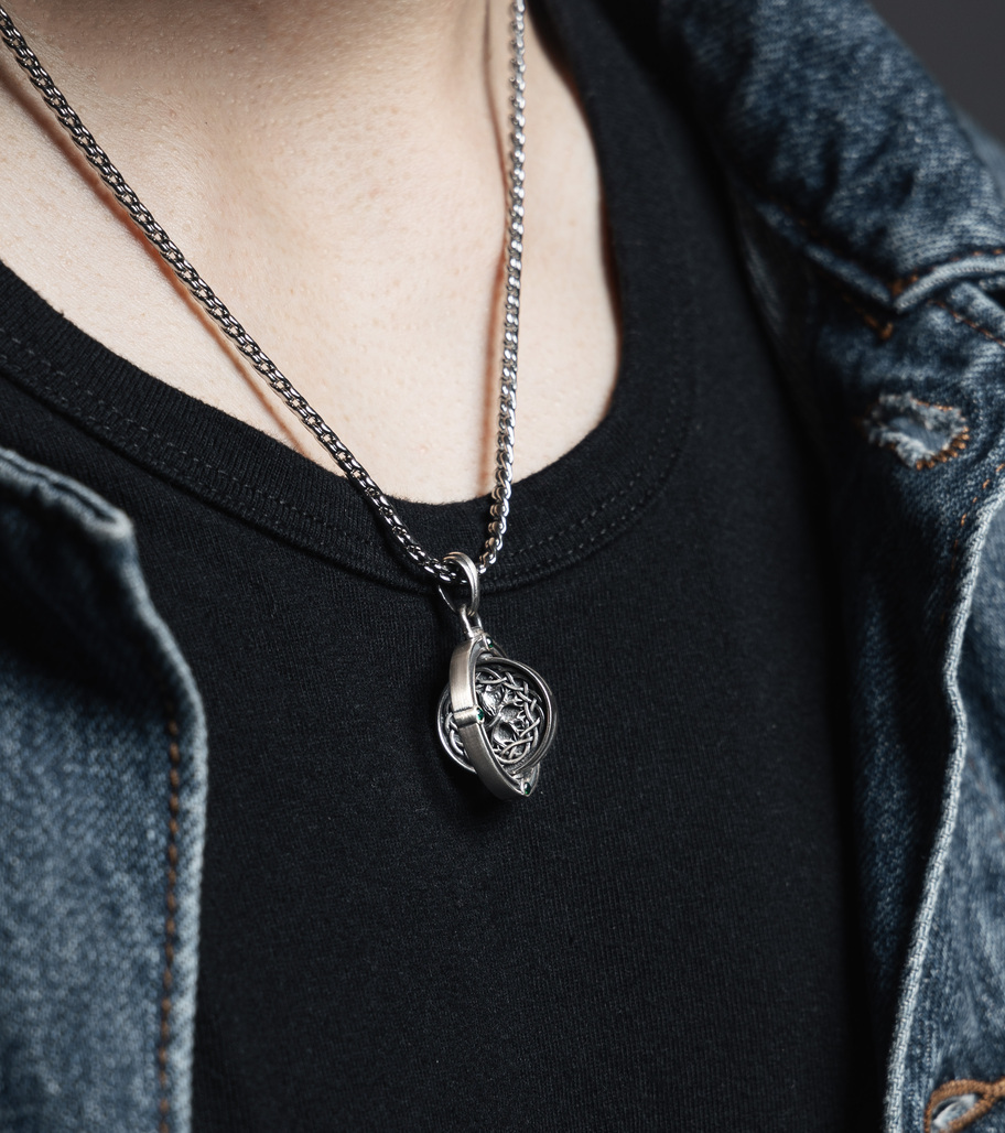 靈識之輪 純銀旋轉墜 The Wheel of Consciousness Pendant，佩戴於黑色T恤與牛仔外套穿搭中，展現凱爾特結與生命之樹的靈性設計，綠寶石鑲嵌細節凸顯質感與象徵意義