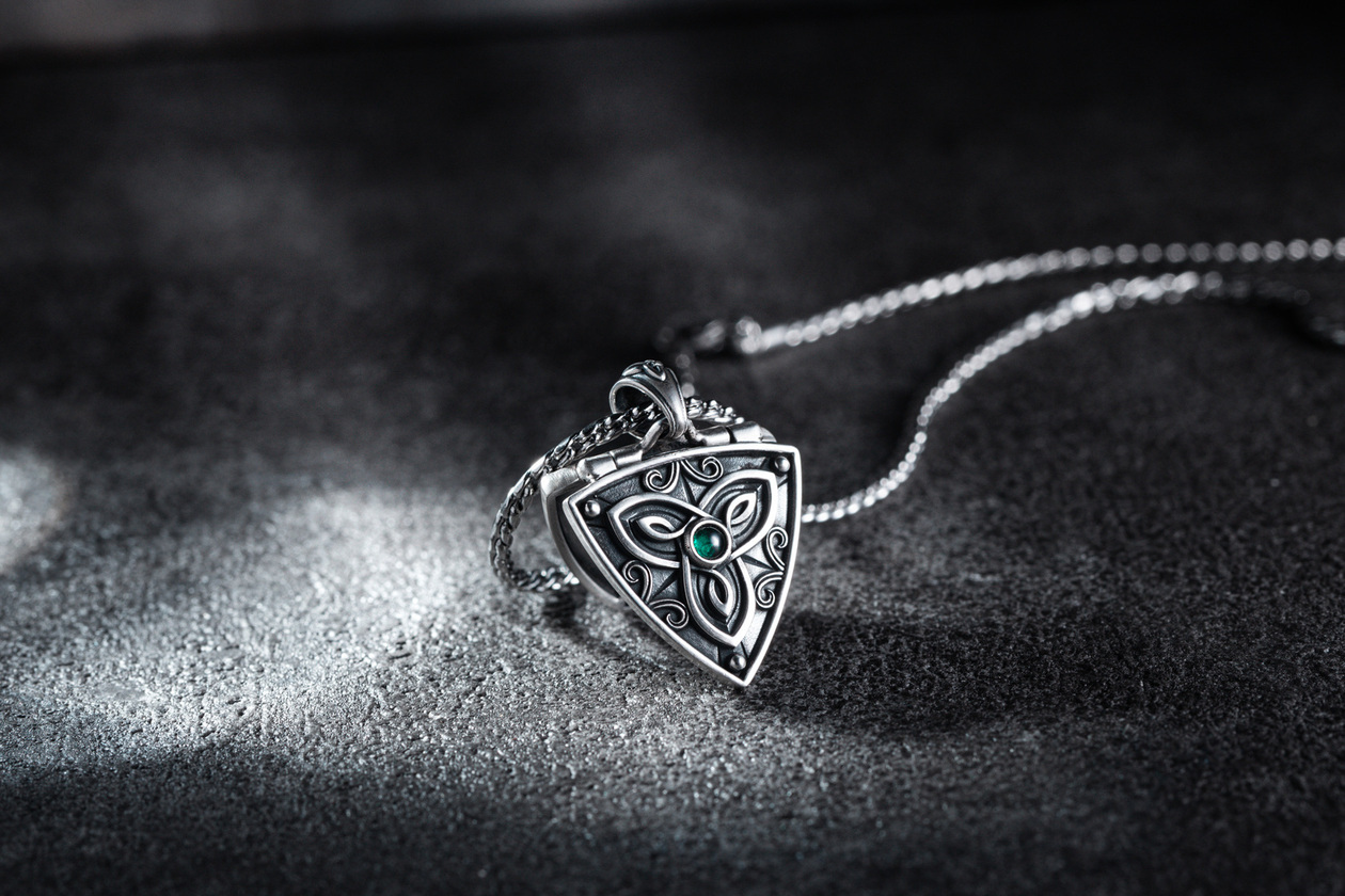 聖靈樹盾 開合純銀吊墜 Guardian Tree Shield Silver Locket，盾牌造型融合凱爾特三位一體結與綠寶石核心設計，象徵靈魂守護與內在回歸的純銀吊墜，靜置於石紋背景下展現沉穩靈性質感
