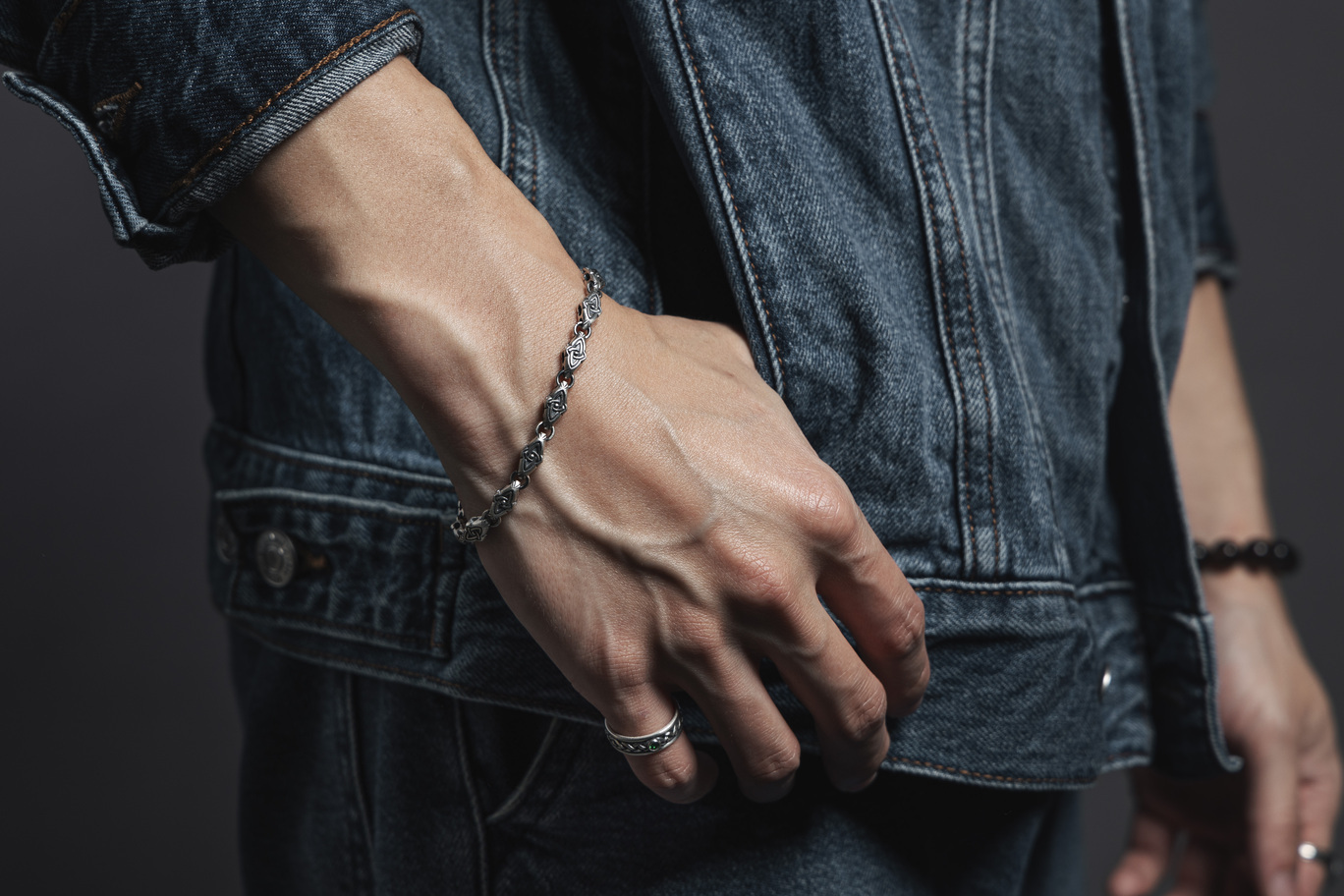 時光之鏈 純銀手鍊 The Chain of Time Silver Bracelet，手鍊以凱爾特三位一體結造型環扣連結而成，象徵時間與靈魂片刻的串聯，圖為男性日常穿搭實拍，搭配牛仔外套呈現低調靈性風格與銀飾質感穿搭