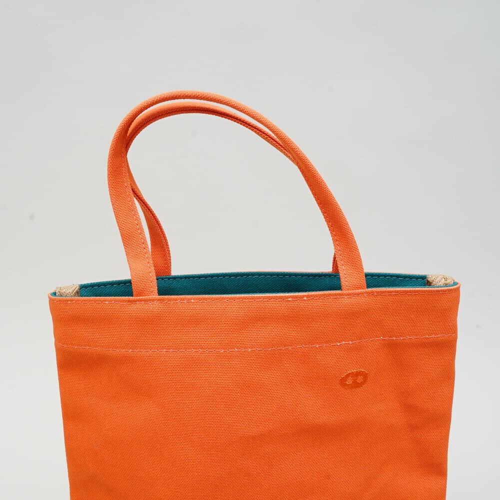 甘單小包柿子橘色帆布手提包正面展示，小巧袋型搭配蘑菇經典剪裁