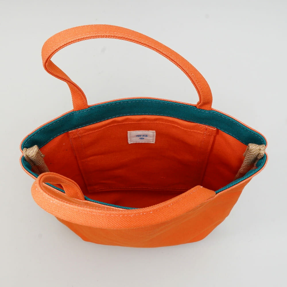 甘單小包柿子橘色帆布手提包正面展示，小巧袋型搭配蘑菇經典剪裁