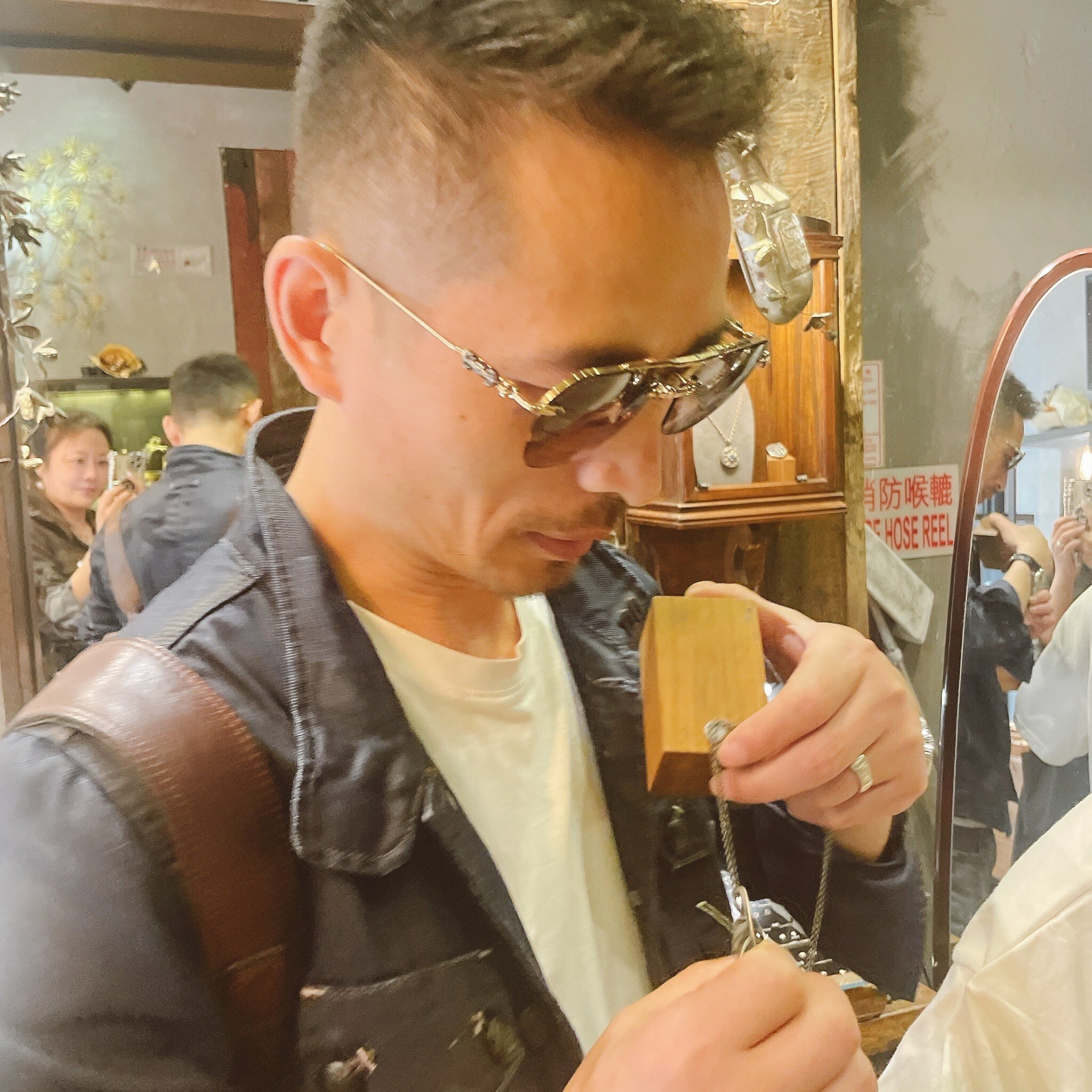 顧客於Silversmith香港銀飾店細看手工純銀項鍊,展櫃中陳列精緻銀飾,店內鏡面與擺設營造溫暖復古氛圍