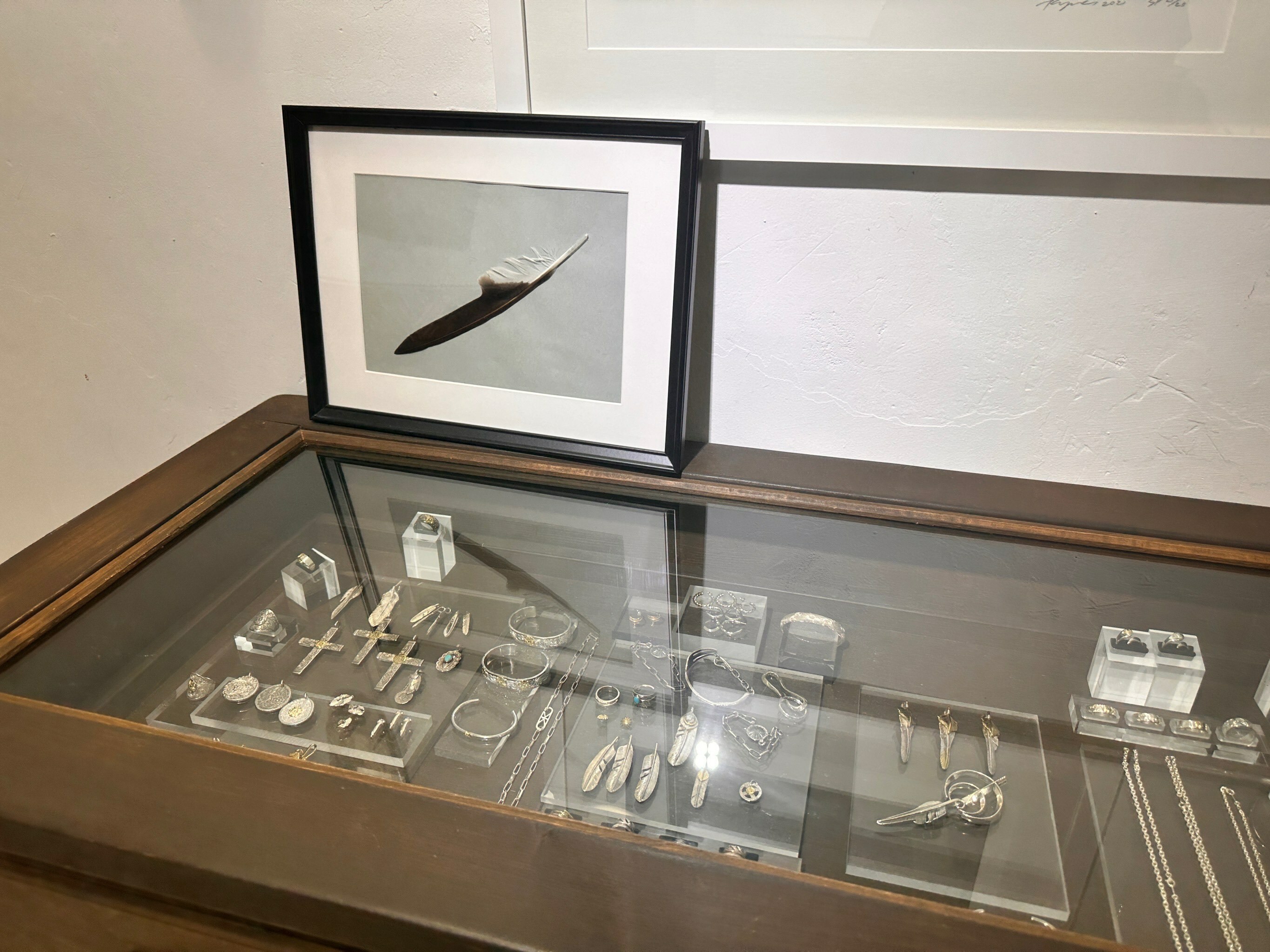vinavast香港銀飾店內羽毛主題展櫃,搭配藝術羽毛掛畫,陳列多款鷲見太郎風格銀飾與精緻吊墜