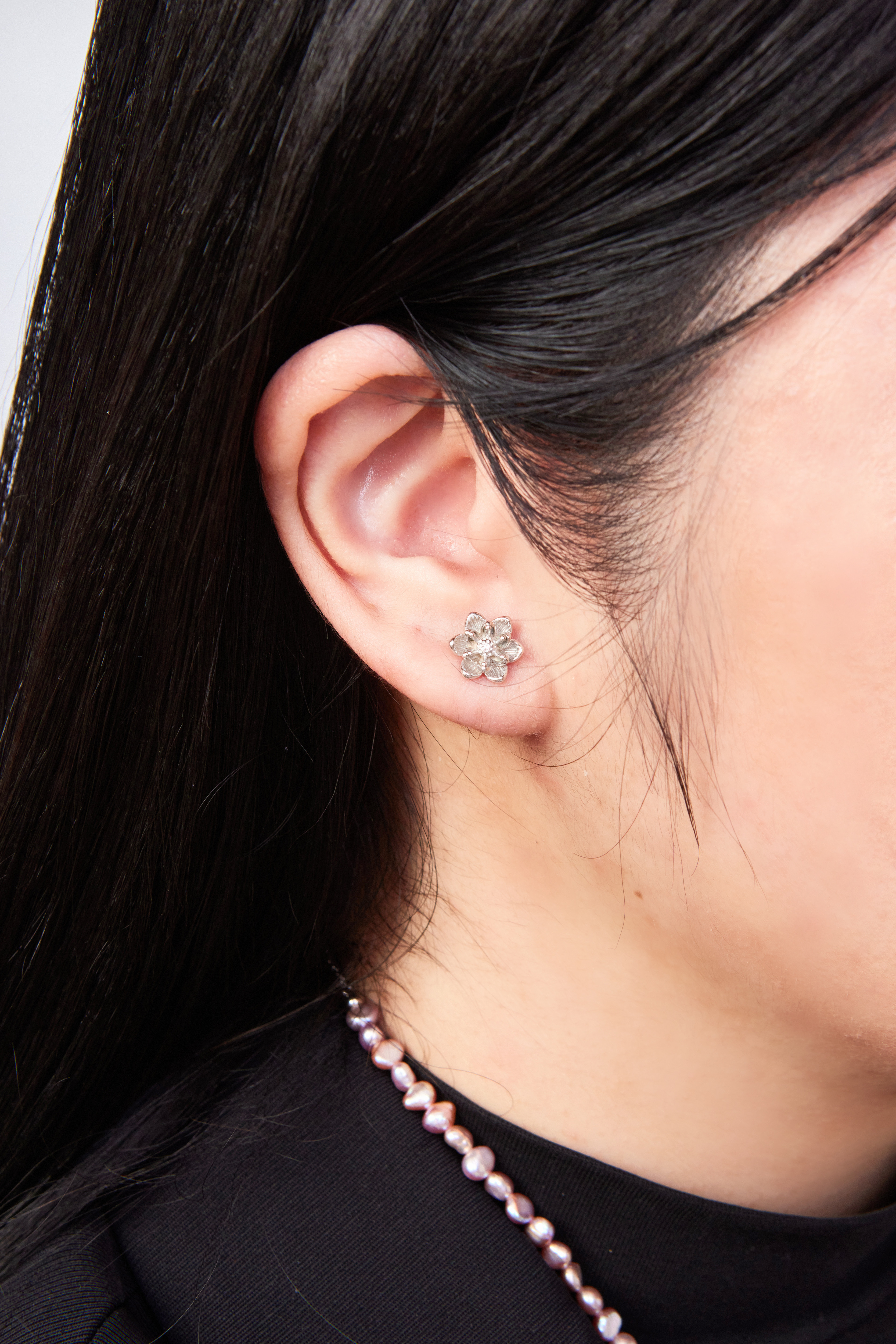 純銀花朵耳環佩戴於耳垂側面特寫，花瓣造型清晰可見