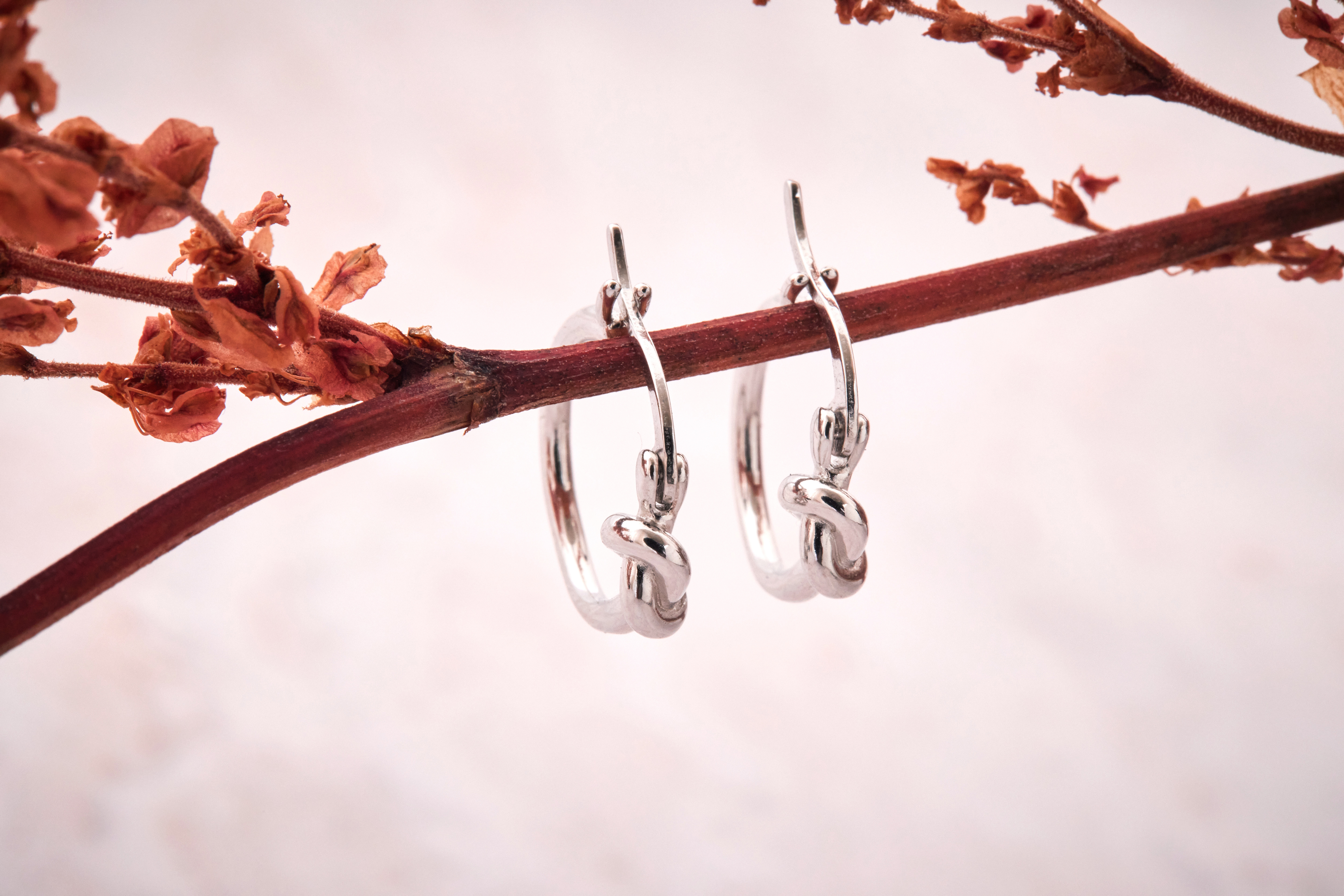 純銀紐結壓扣耳環飾品單品照，展現光澤金屬質地與立體造型