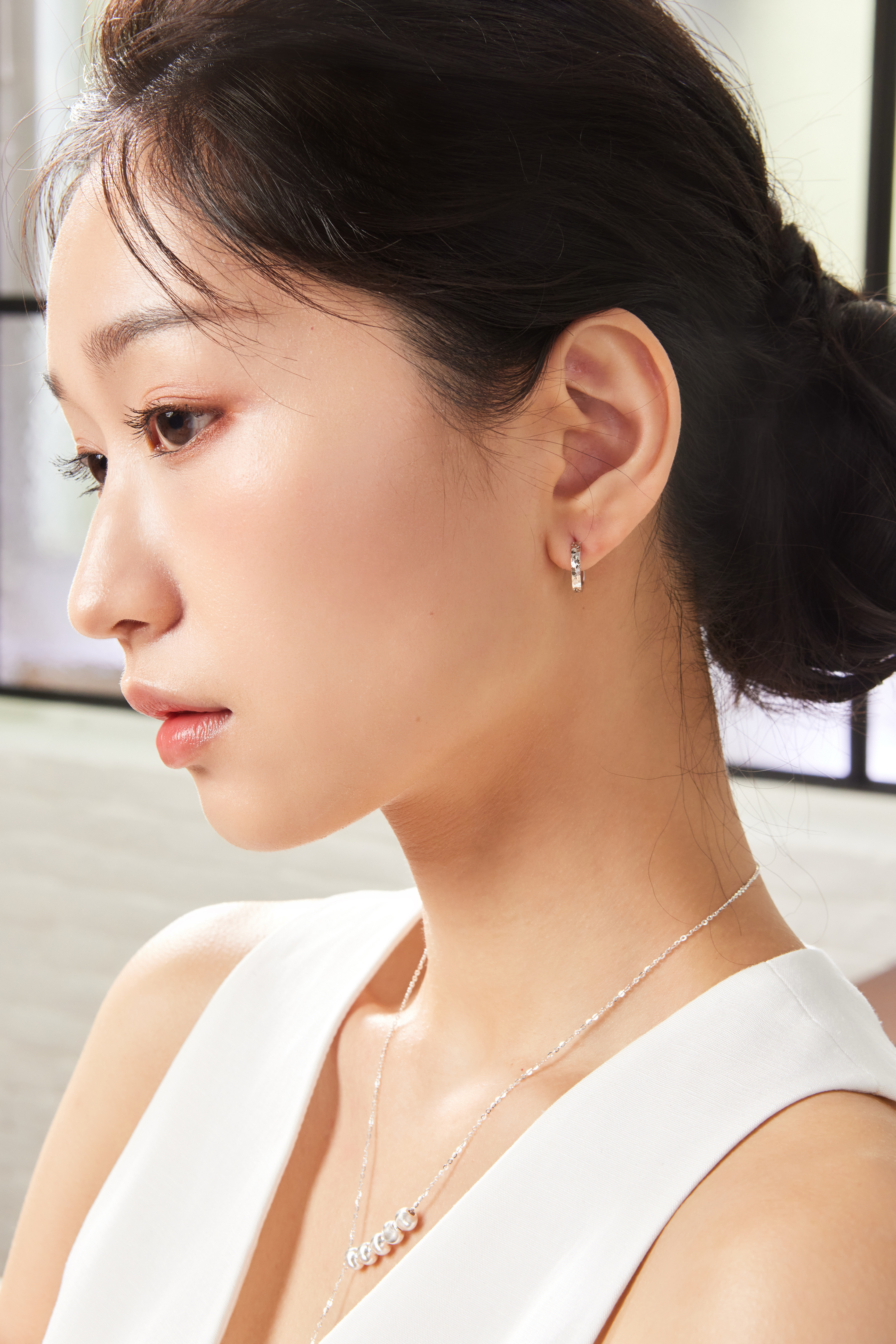 模特側臉佩戴切割亮面耳環，金屬光澤與臉部線條相襯自然