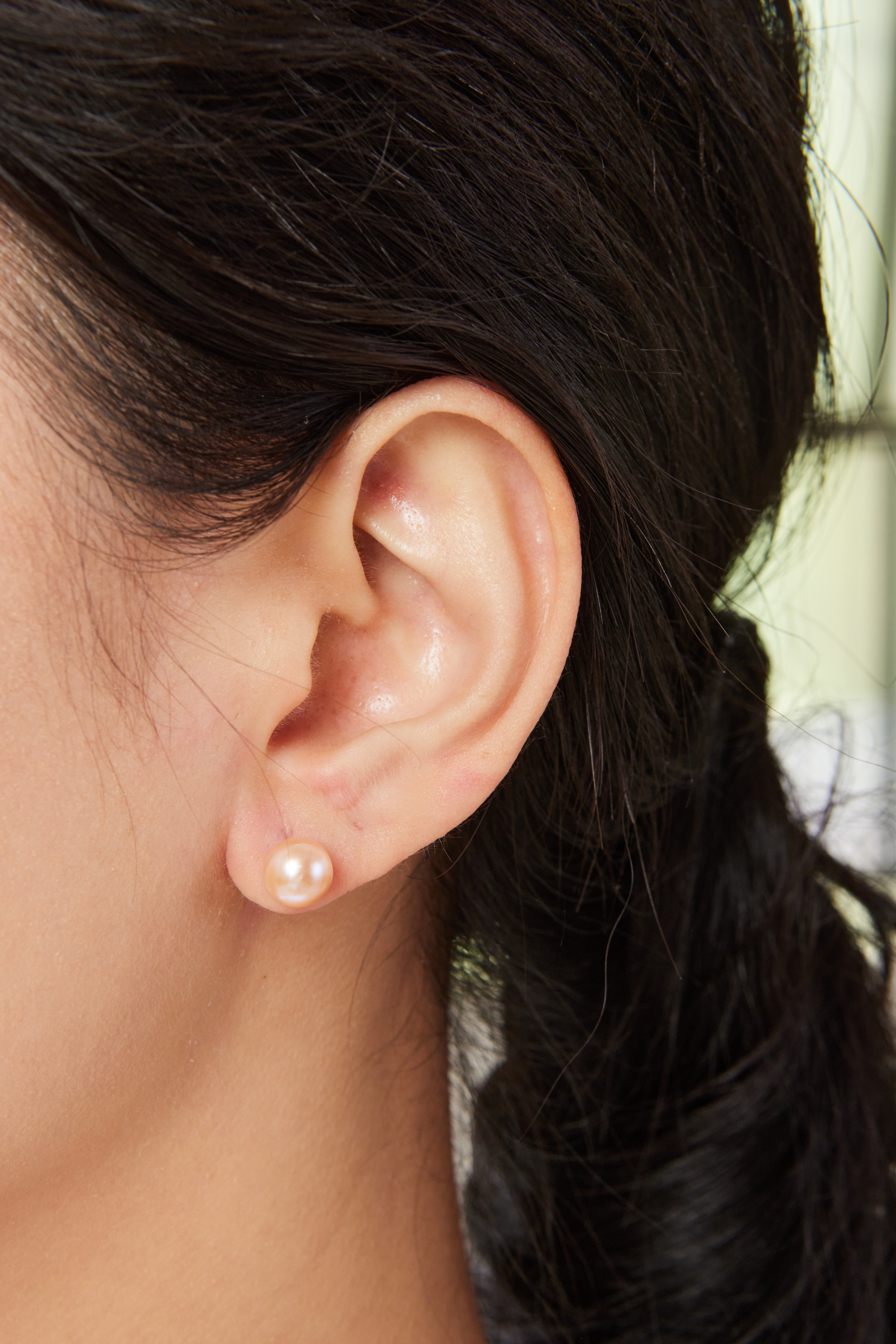 模特佩戴 8–8.5mm 橘粉珍珠耳環，自然霧光中帶有圓潤存在感