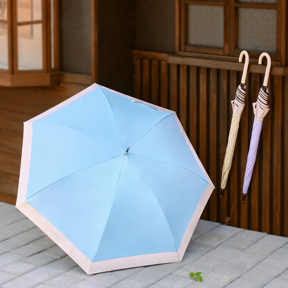 三把傘放在日式木造建築外，一把藍色傘撐開放在地上，另兩把分別為黃色與紫色傘收起掛在牆上