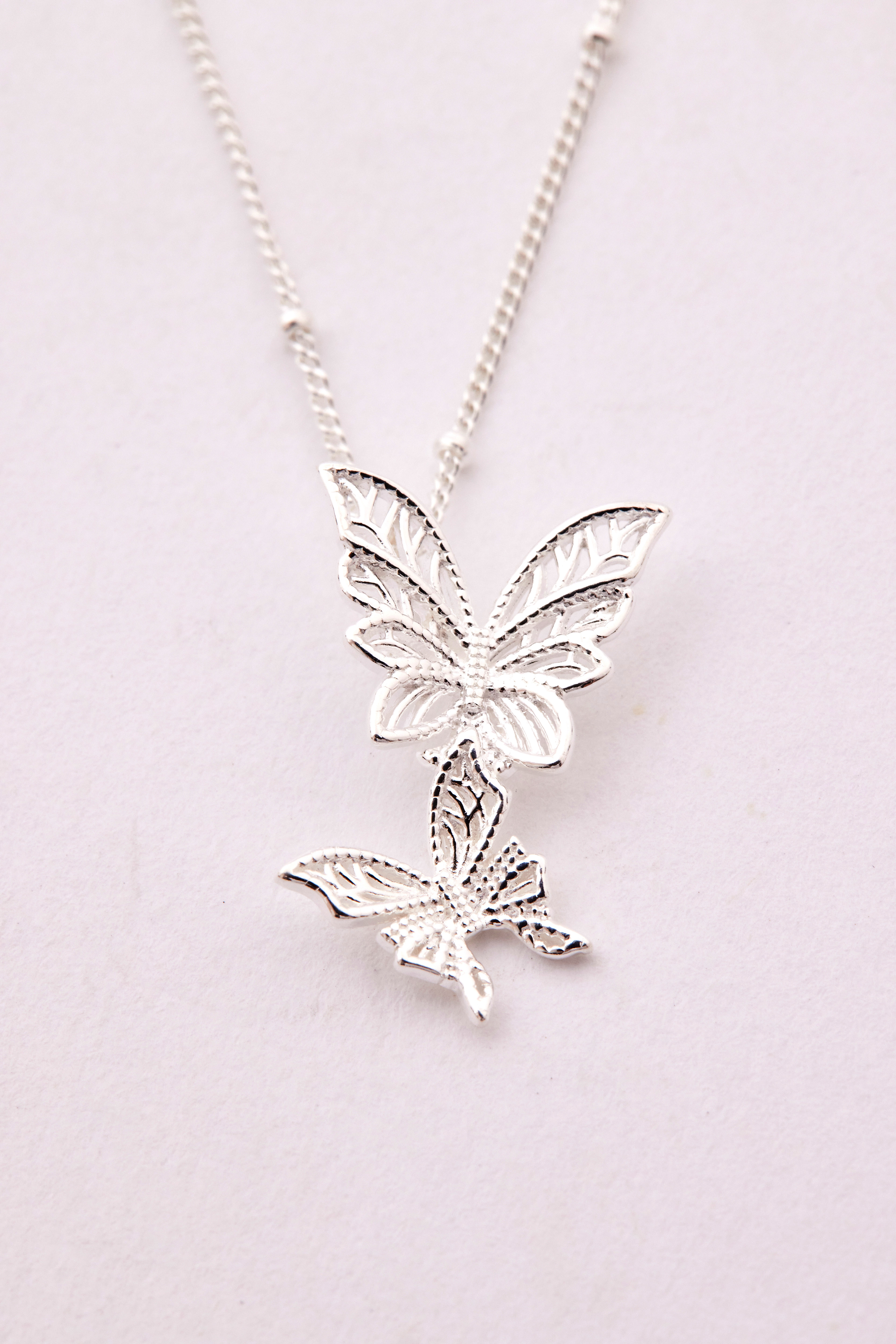 蝴蝶吊墜特寫照，呈現兩隻蝴蝶翅膀層疊的立體感