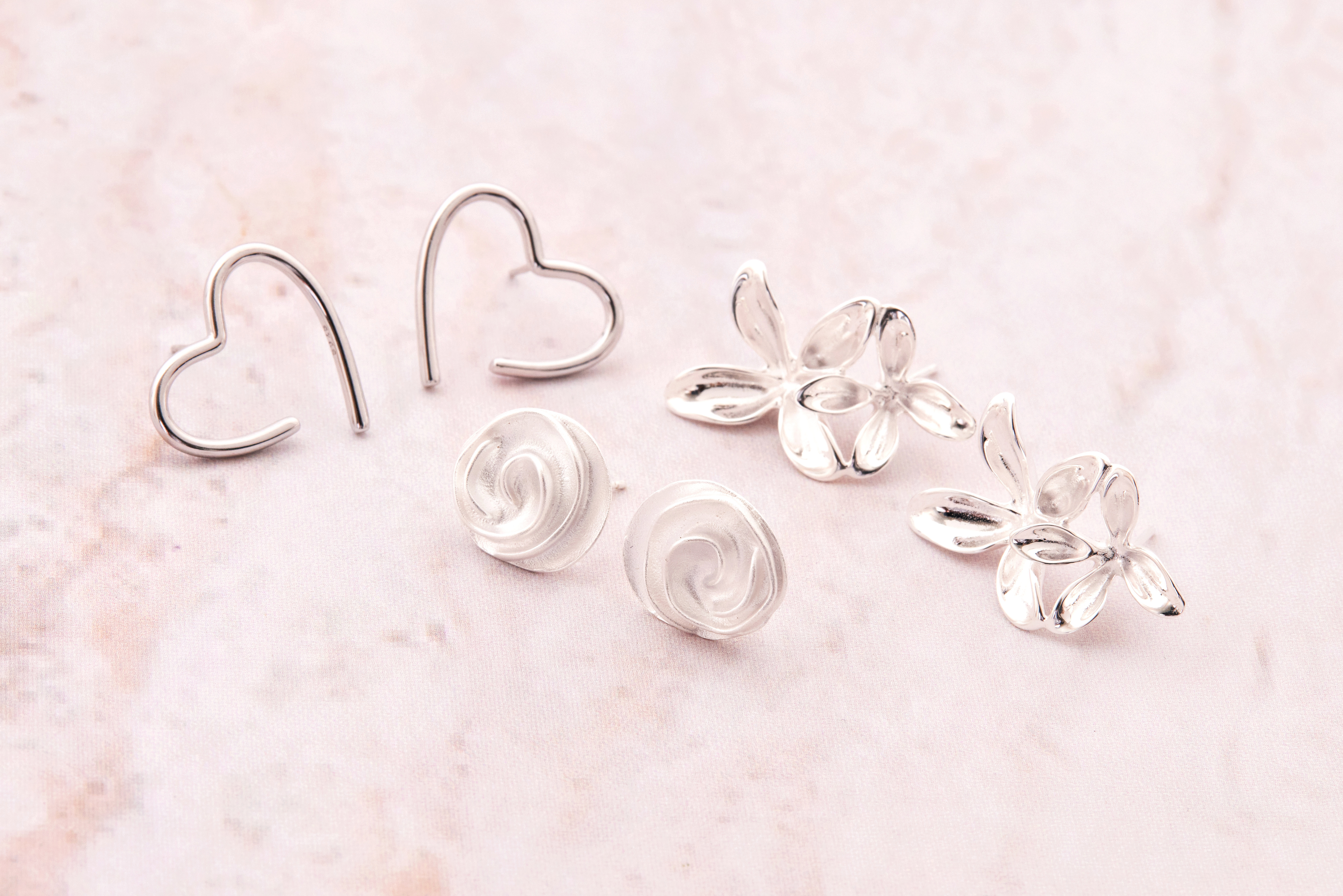 純銀愛心耳環與其他款式耳環合照，展現系列飾品多樣風格與光澤對比