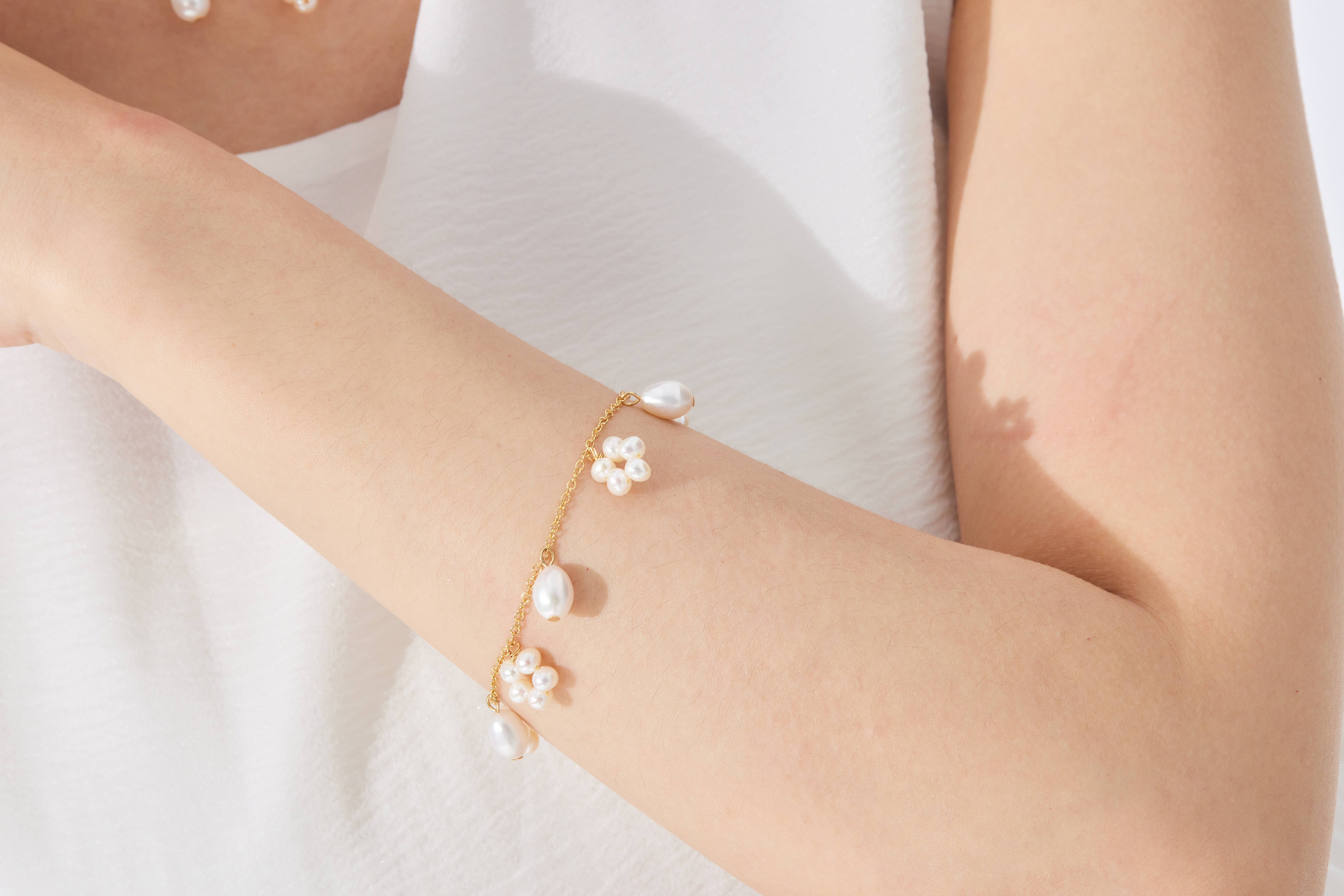 模特手腕配戴手鍊特寫，突顯珍珠與金屬光澤