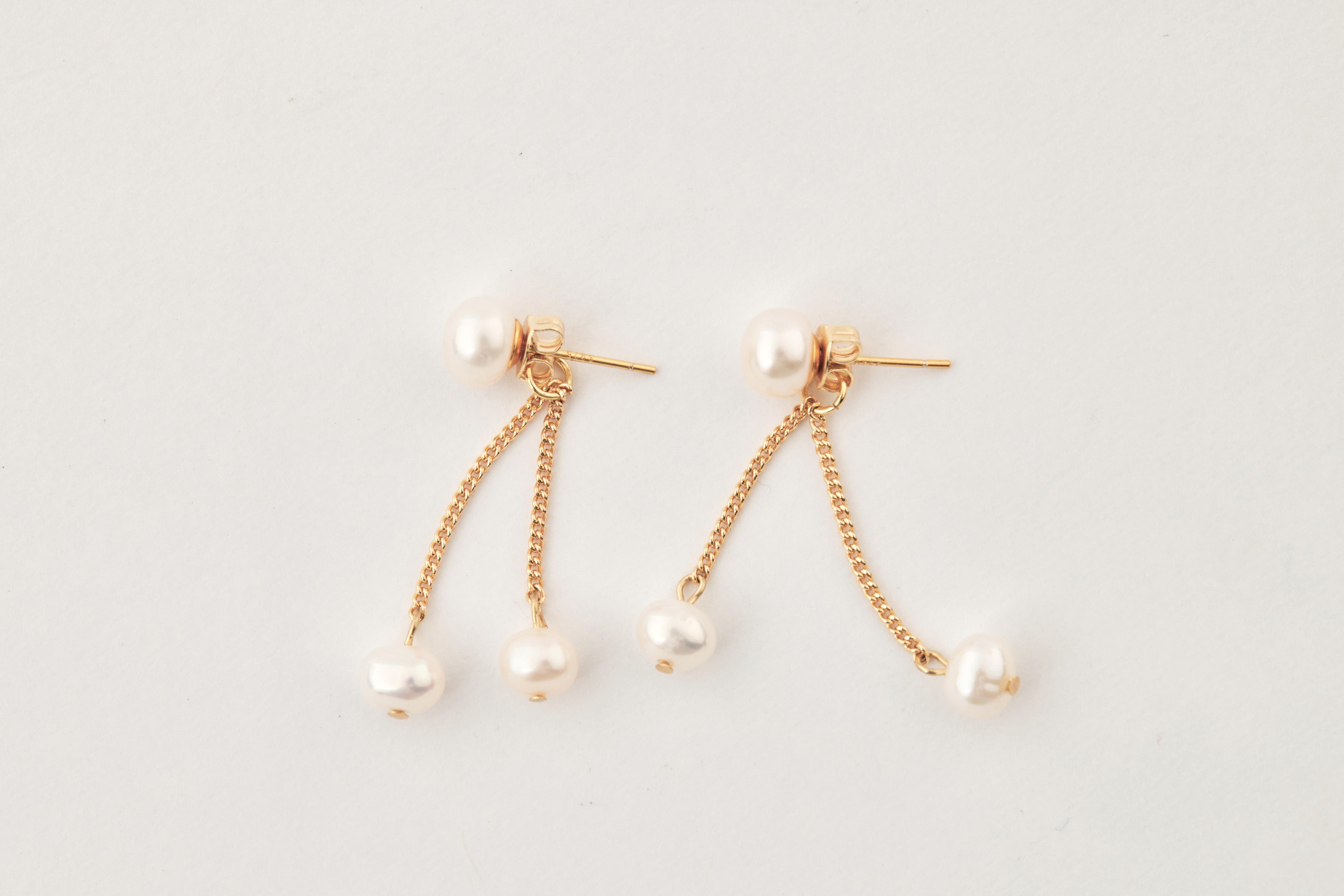 耳環擺放於白色背景，呈現14kgf金屬與珍珠質地