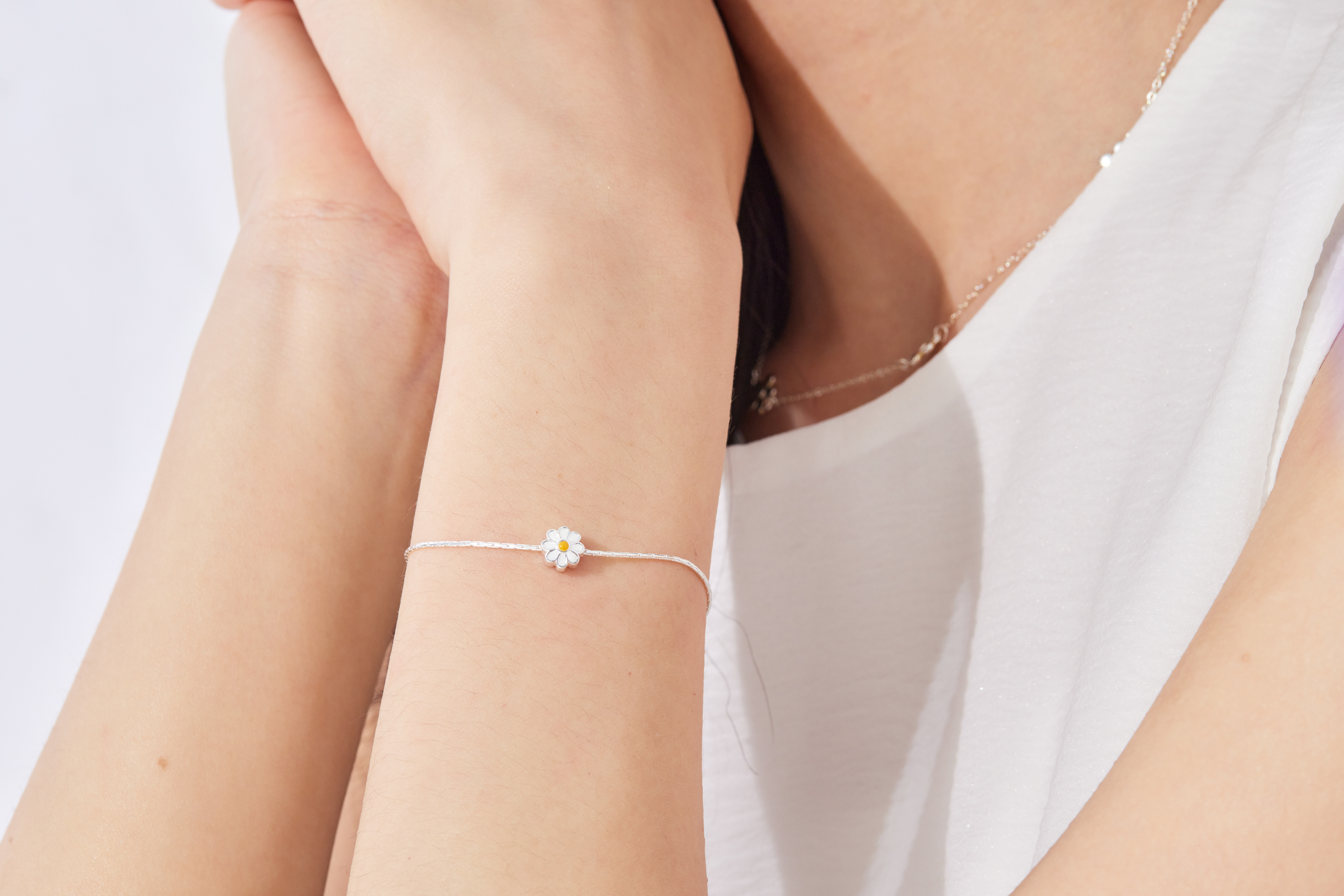 模特手腕佩戴手鍊近拍，突顯雛菊細節與手部線條