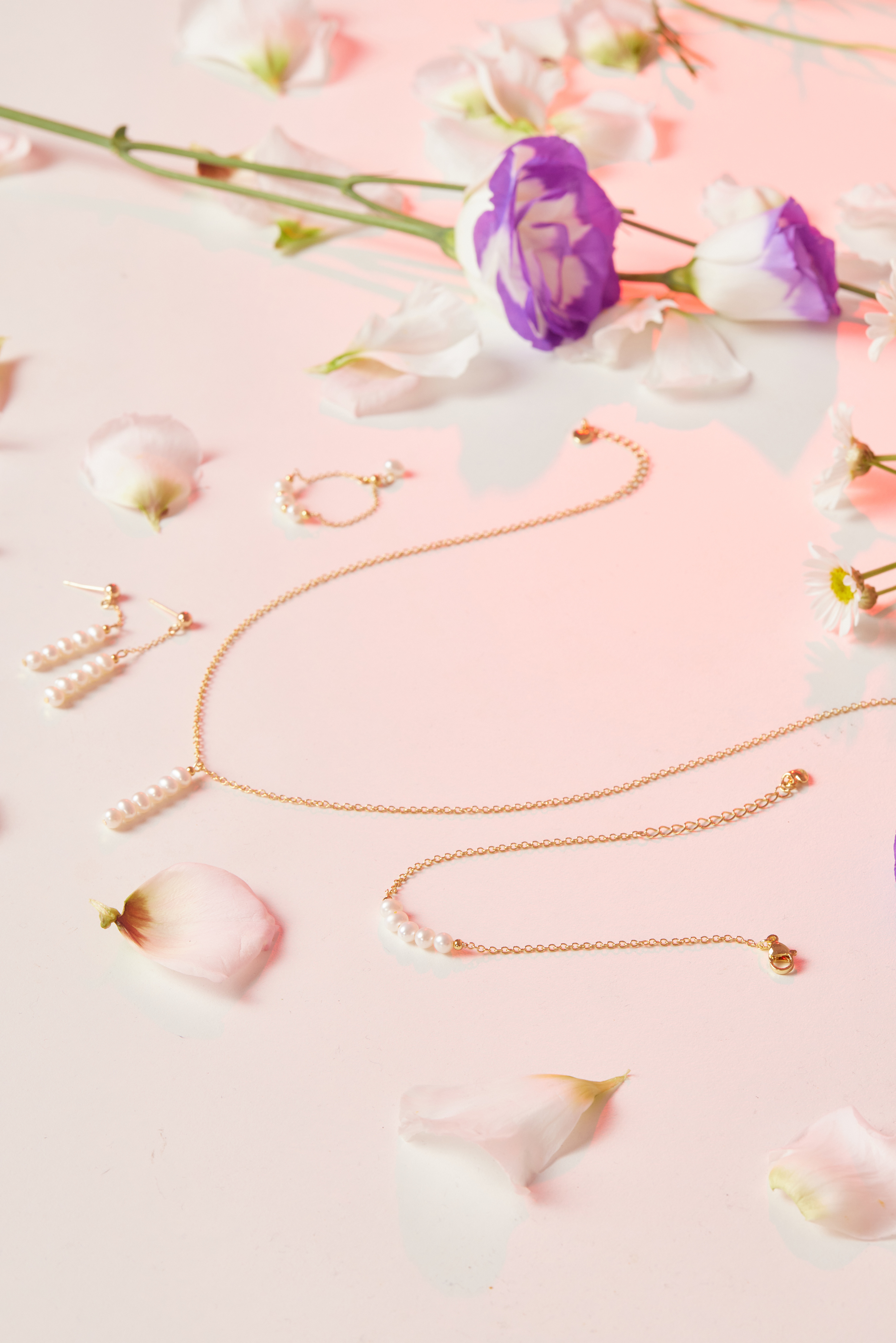 飾品套組與花瓣搭配的氛圍照，細節展現珍珠光澤與14kgf色澤。