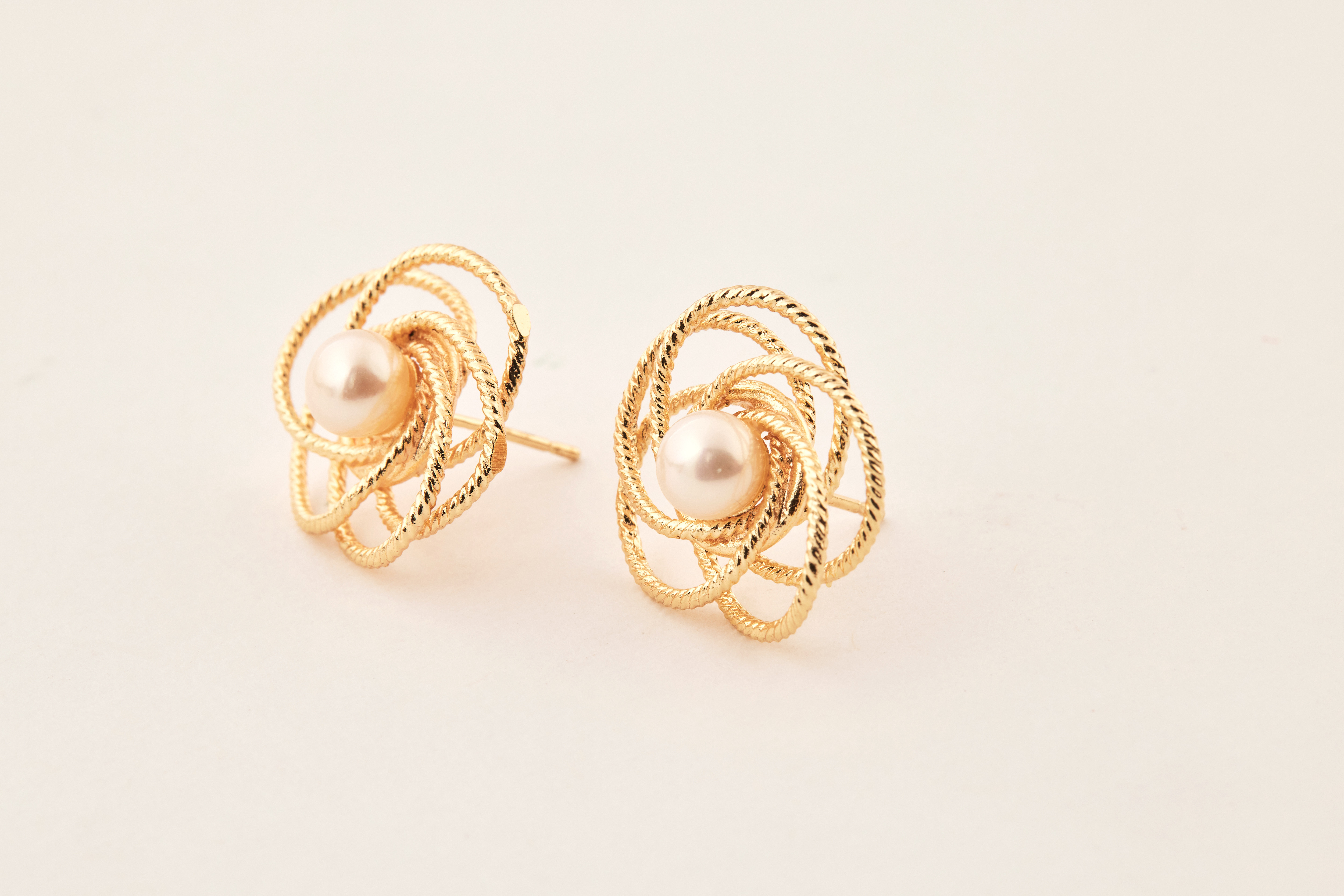 小花淡水珍珠耳環擺放於米色布面，展現自然光澤與細節。