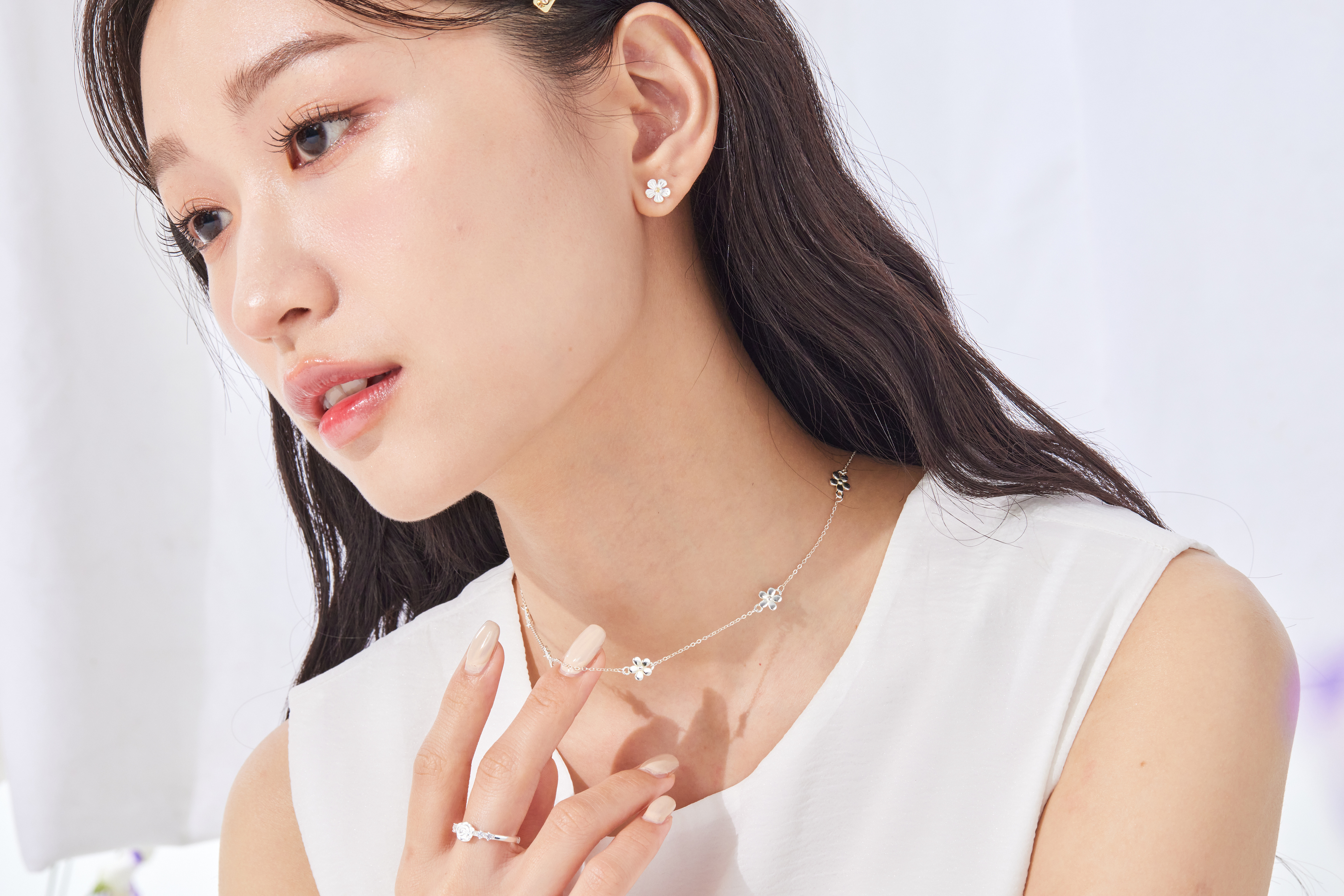 模特伸手撥項鍊，花朵閃耀自然光澤。
