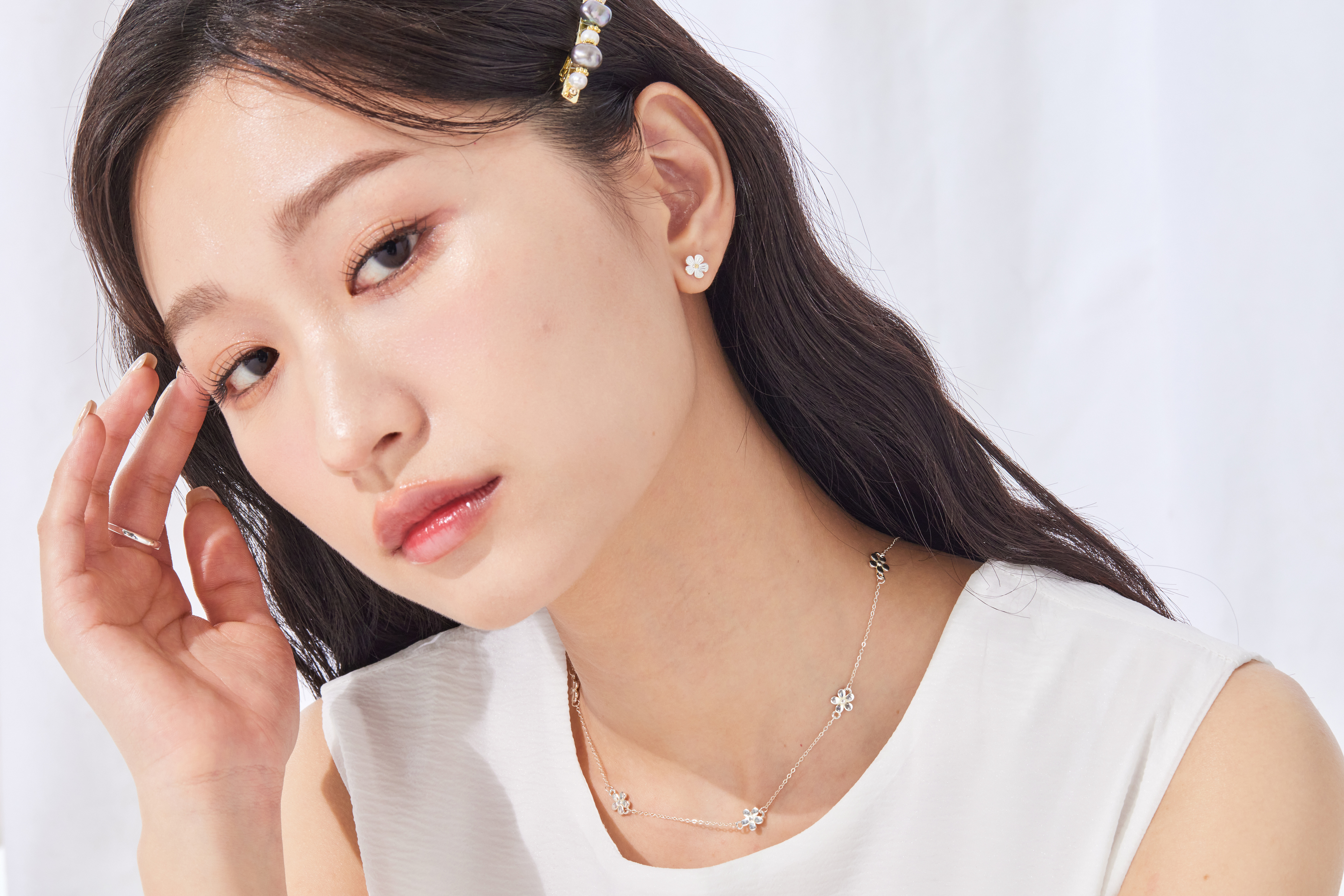 模特身穿淺色上衣，小花項鍊自然垂墜於鎖骨間，散發清新氣息。