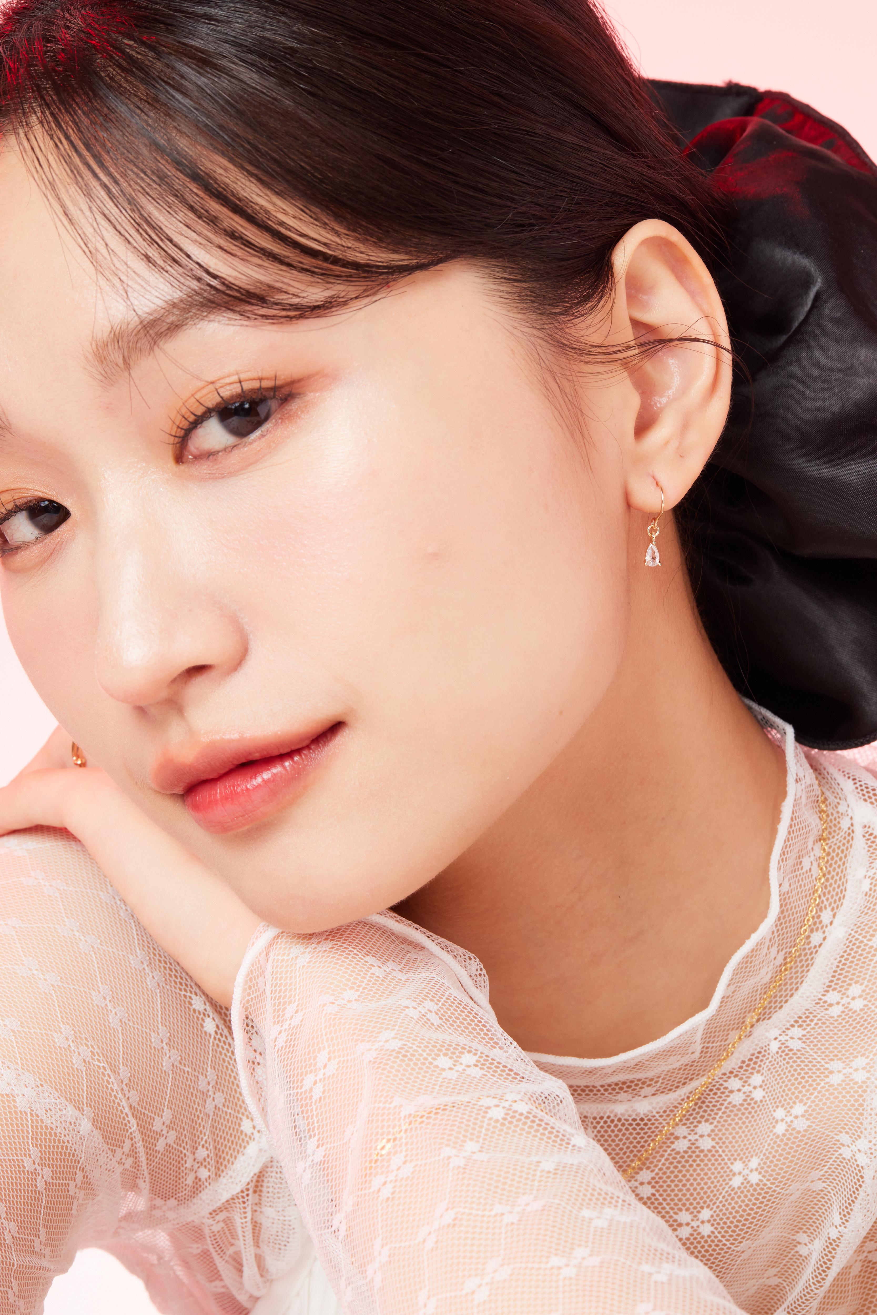 模特髮絲微微掀起，露出閃耀水滴耳環，造型自然柔和。