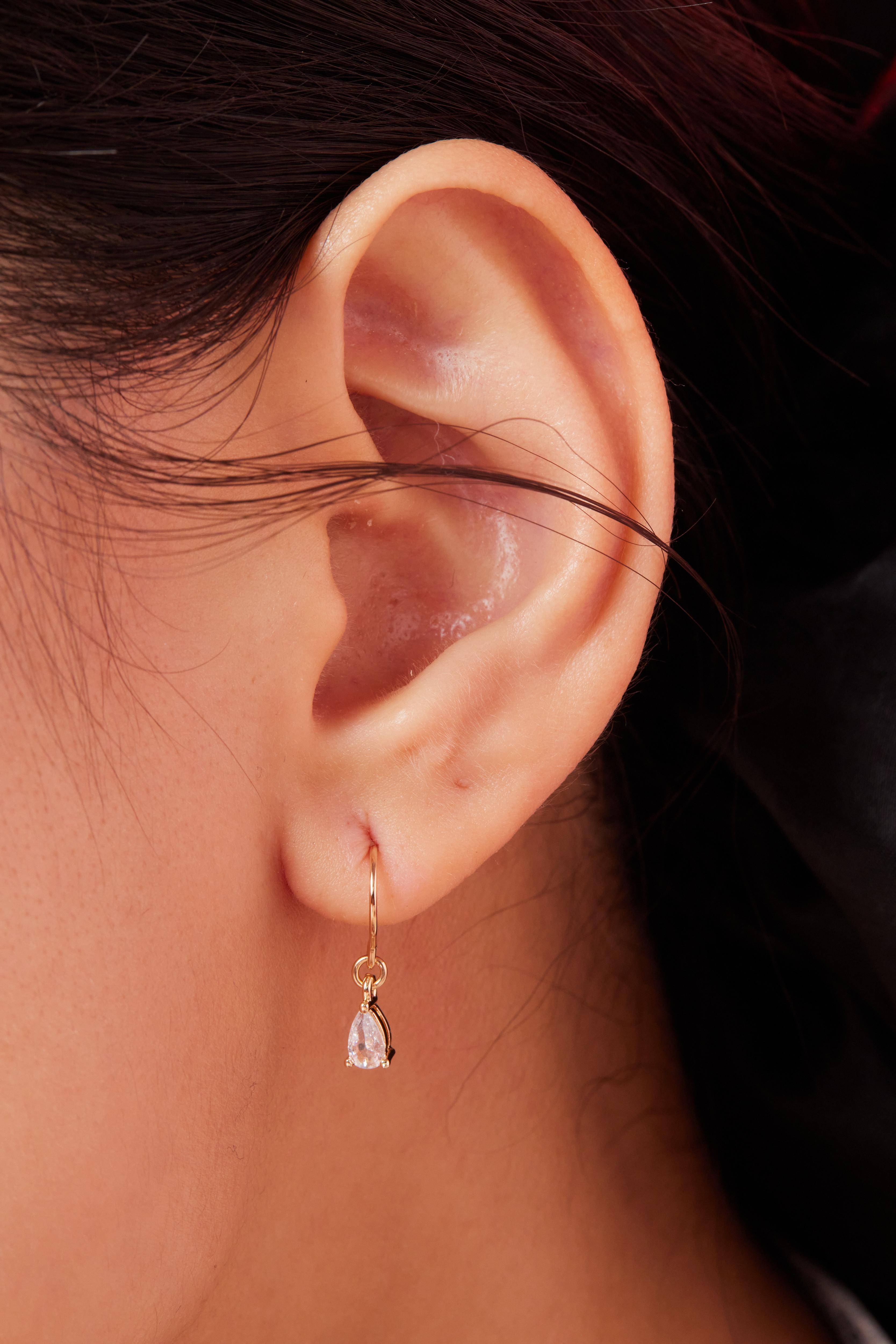 模特耳邊特寫，水滴鋯石自然垂墜，折射出細緻光芒。