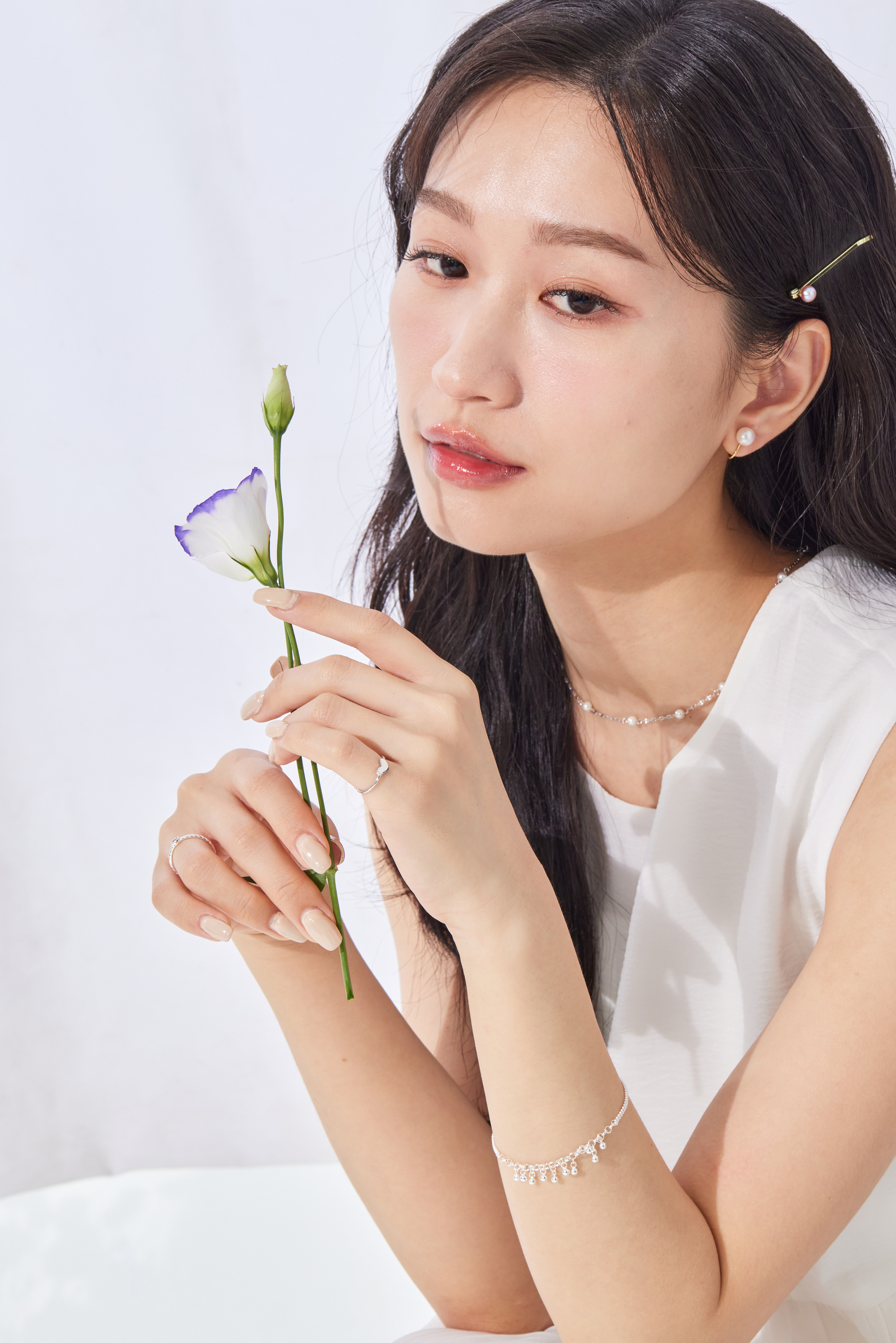 模特手持鮮花，自然搭配銀珠手鍊，日常風格中透露精緻細節。
