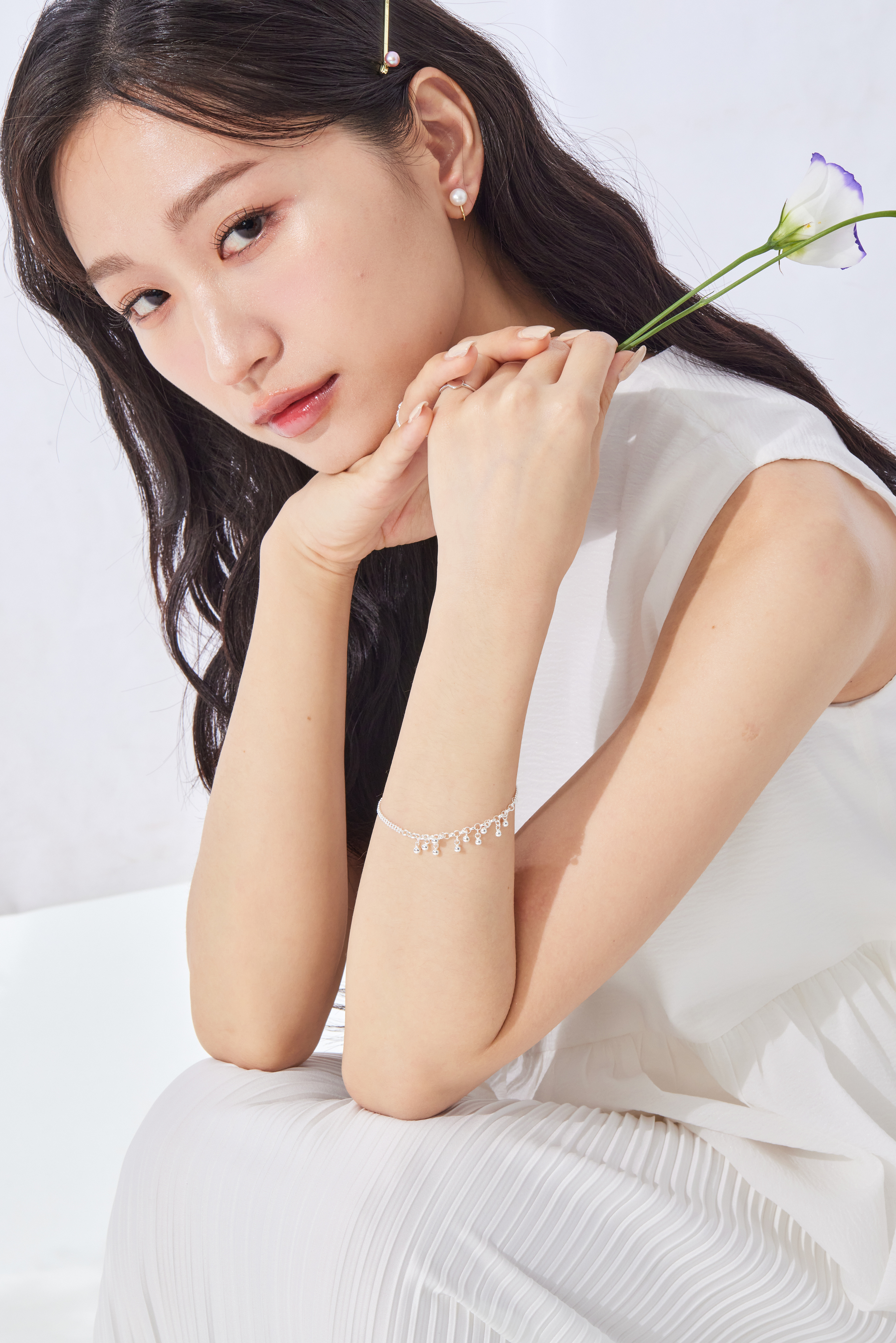 模特搭配簡約珍珠耳環，與銀珠手鍊相呼應，整體造型協調有質感。