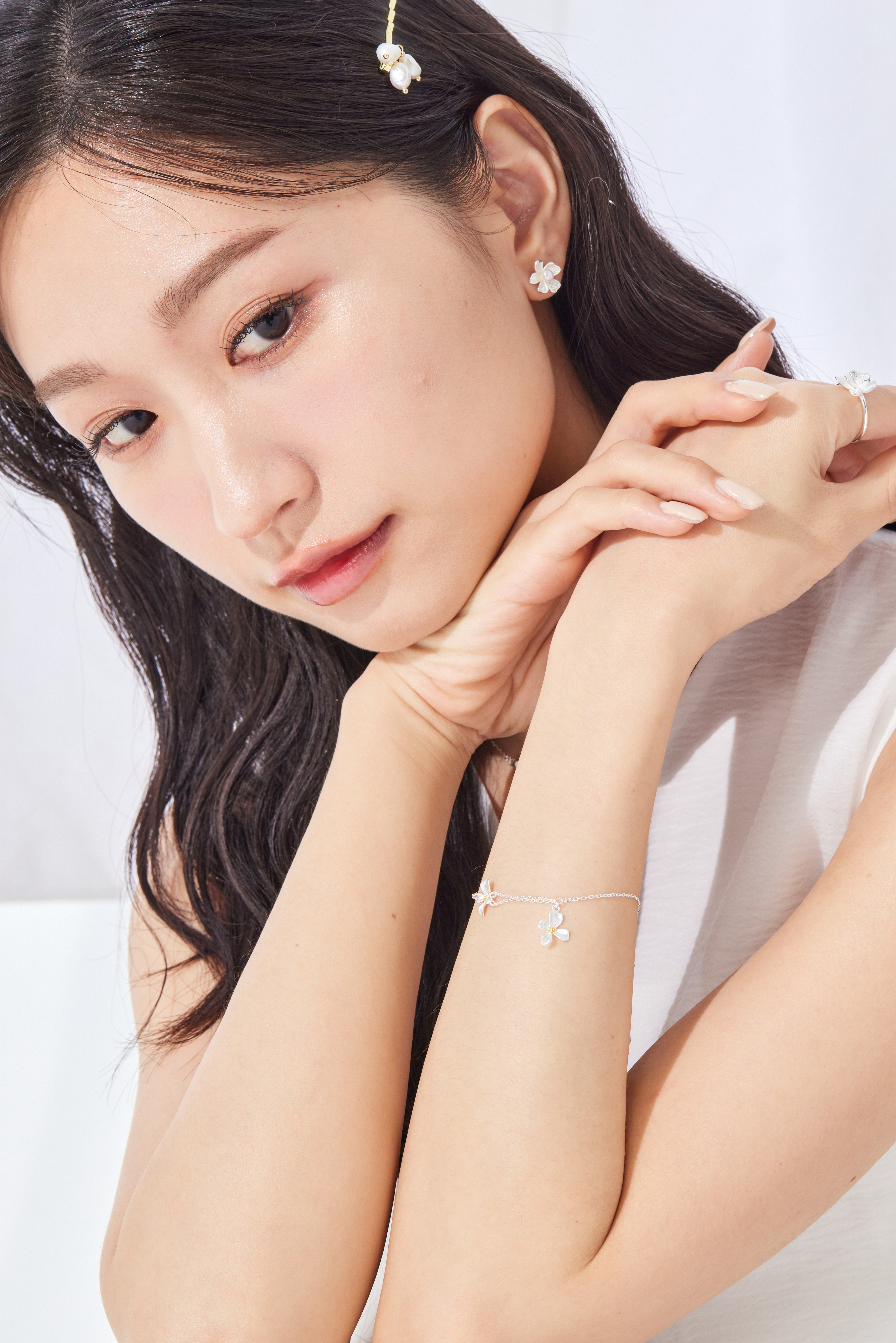 手鍊於腕間隨動作輕晃，雛菊花朵點亮整體穿搭。