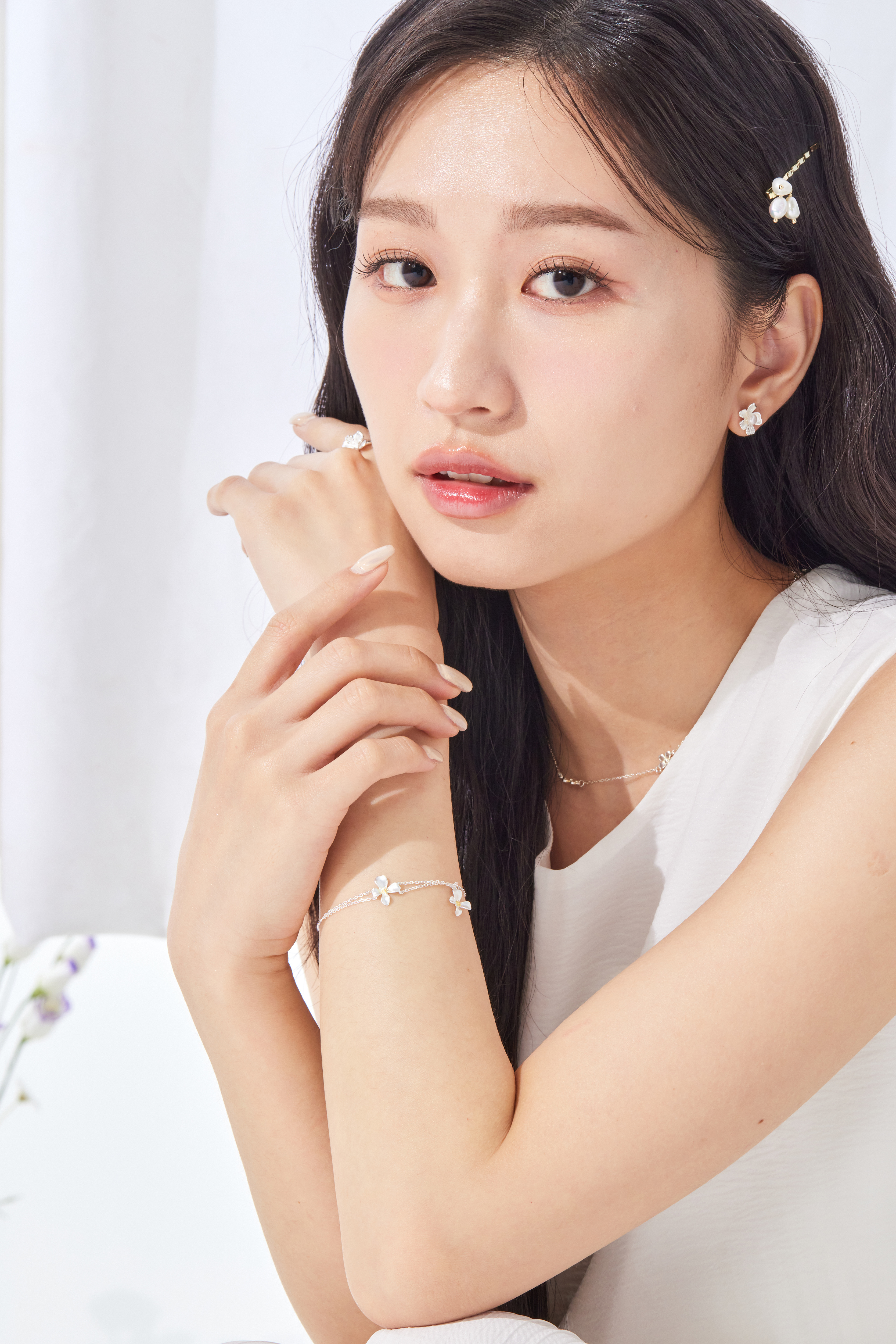 模特穿著白色上衣，輕舉手部展現手鍊整體線條，清新造型感十足。