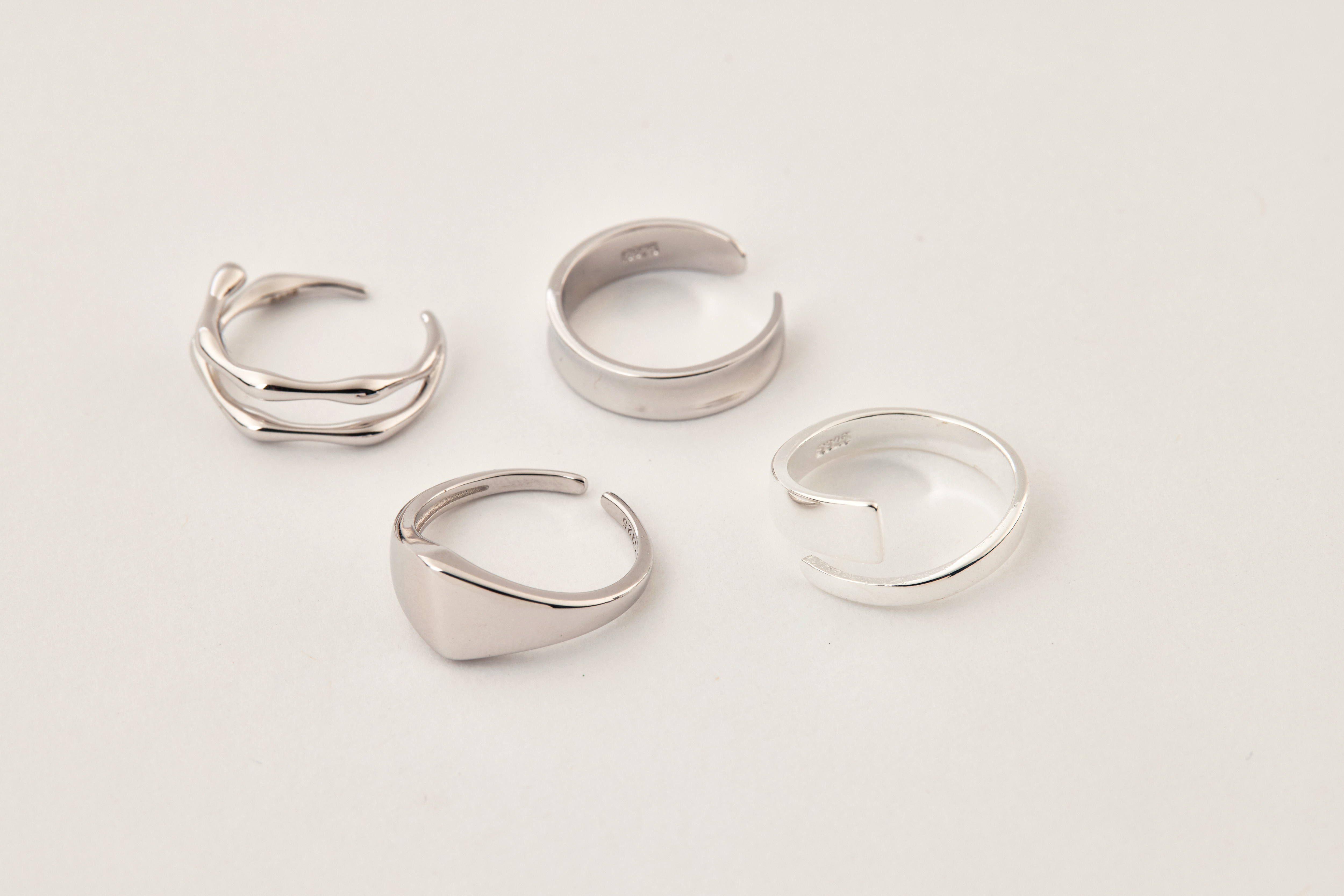 純銀不對稱尾戒與三款簡約風格戒指一同陳列，展現疊戴混搭風格與層次感。