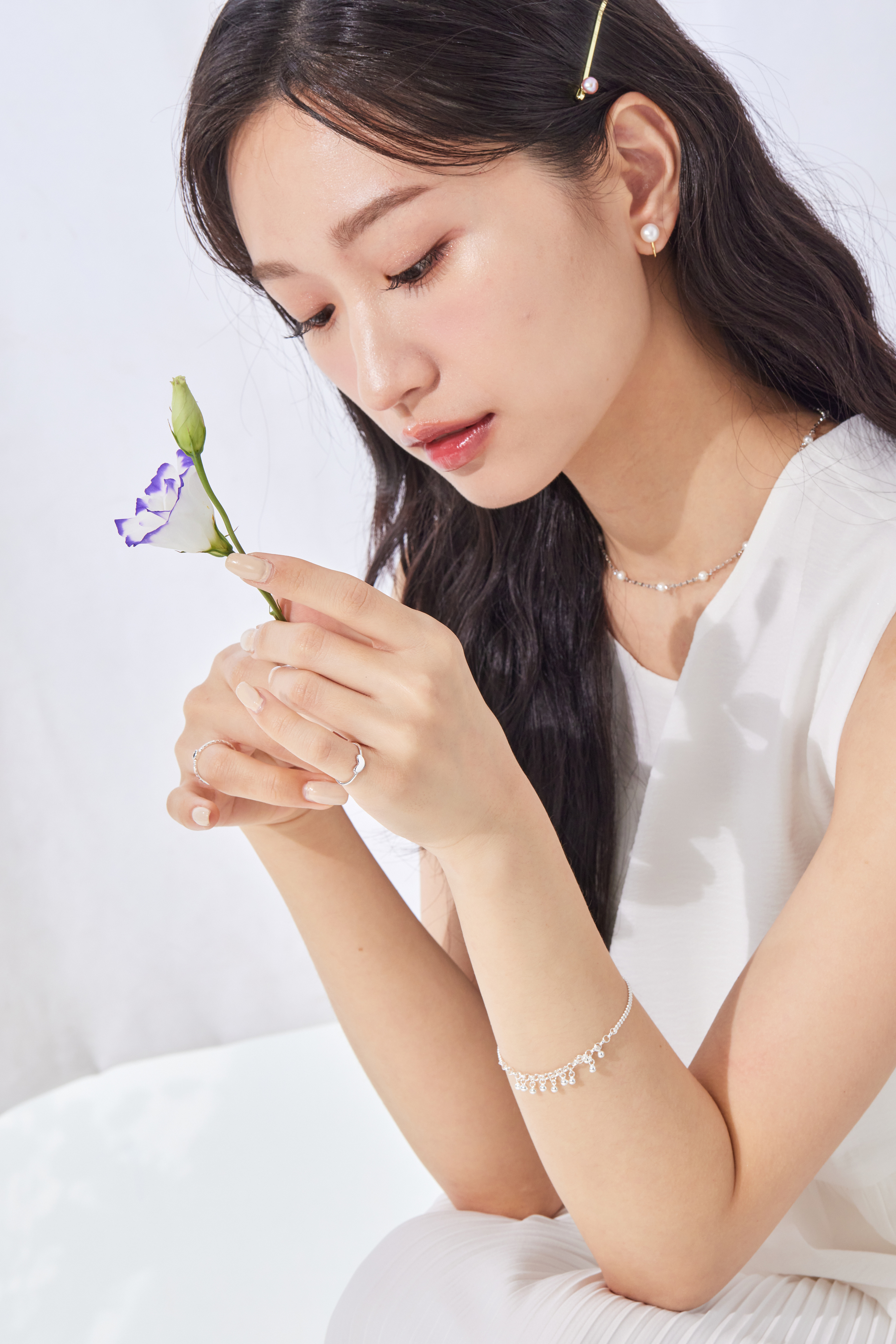 模特手拿著花，尾戒在指尖閃爍純銀光澤，為穿搭增添細節亮點。