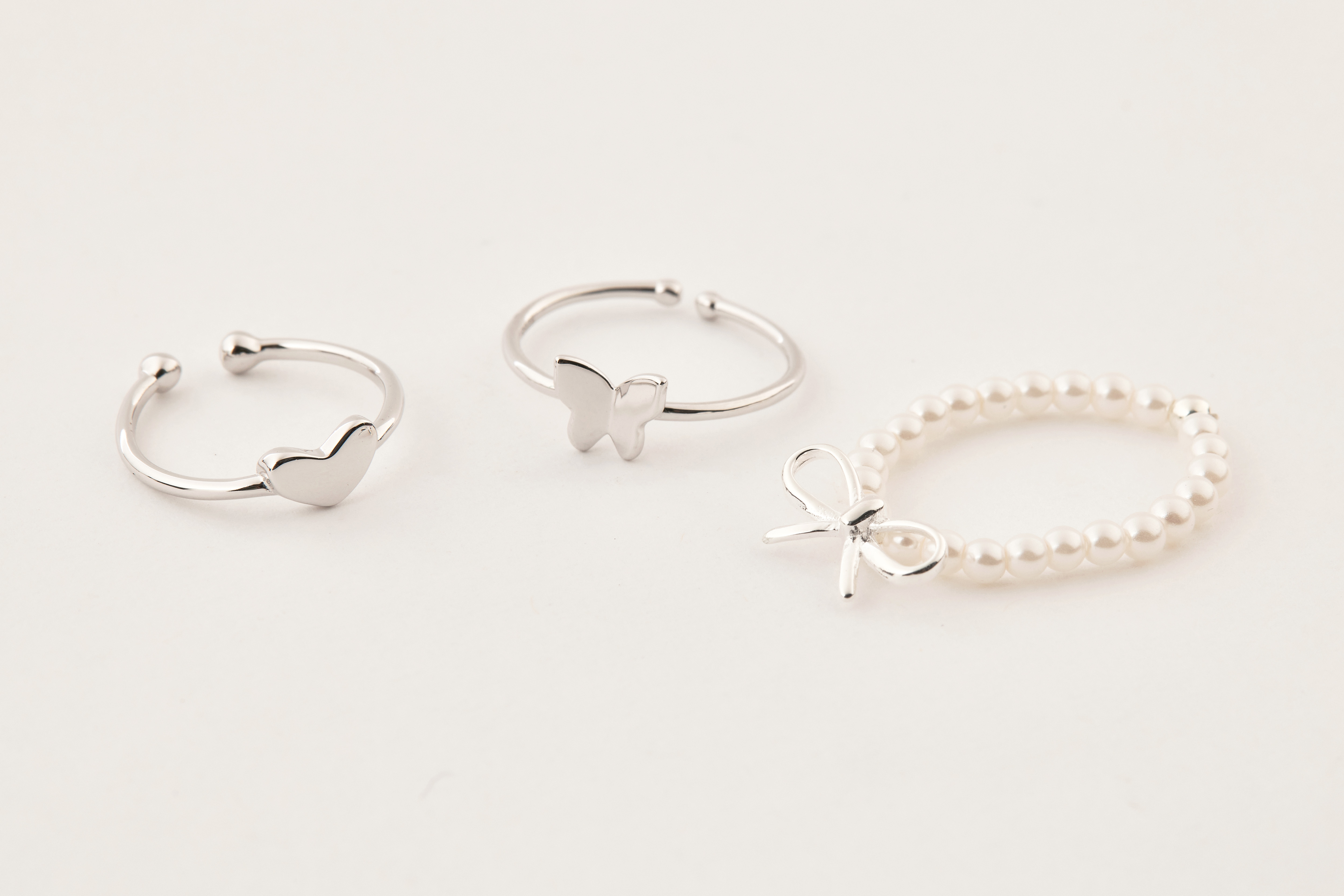 蝴蝶尾戒與愛心尾戒、蝴蝶結珍珠戒指一同擺拍，呈現甜美系戒指疊戴靈感與個性搭配風格。