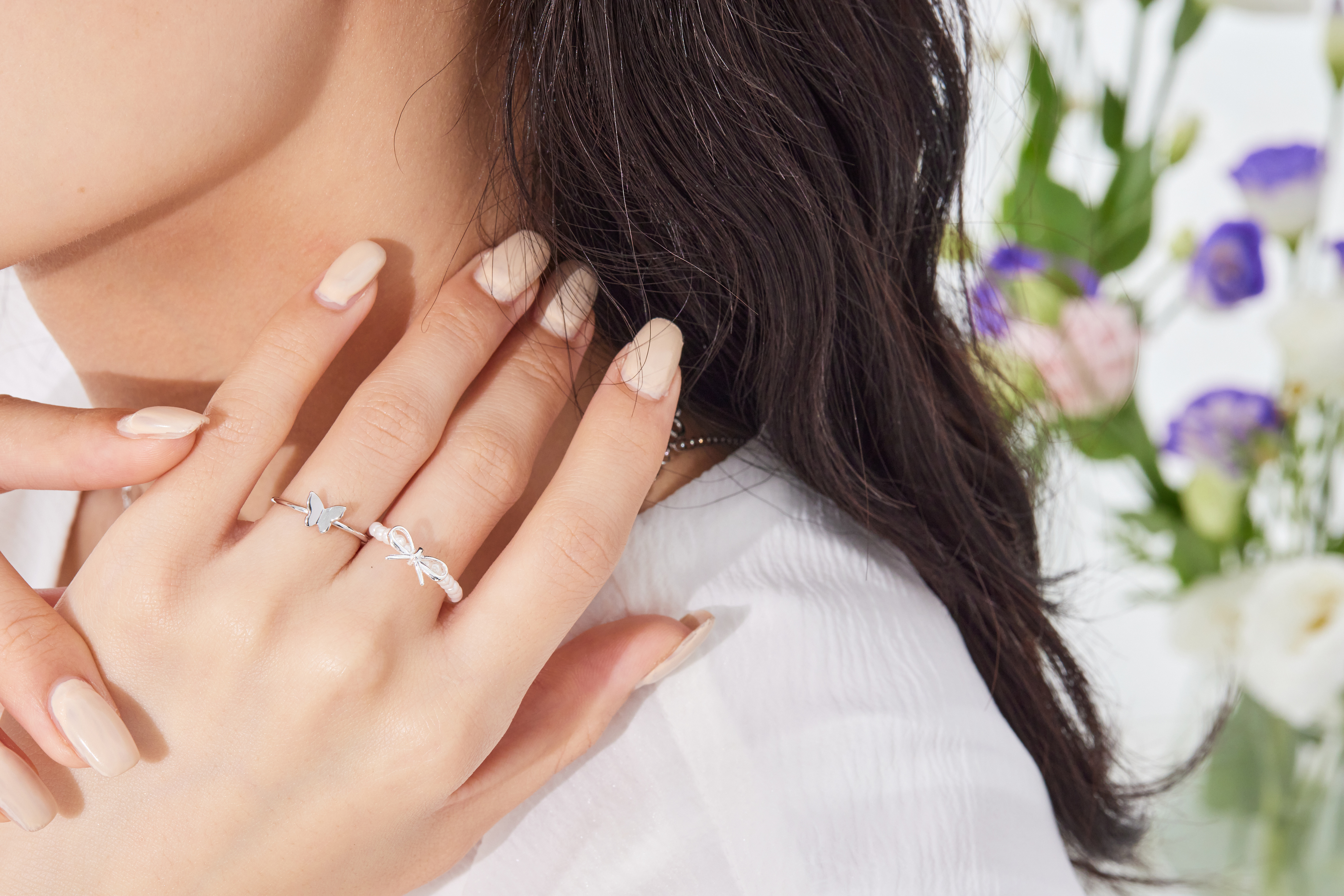 模特指尖微曲，蝴蝶尾戒於自然光中閃爍，營造甜美輕盈氛圍。