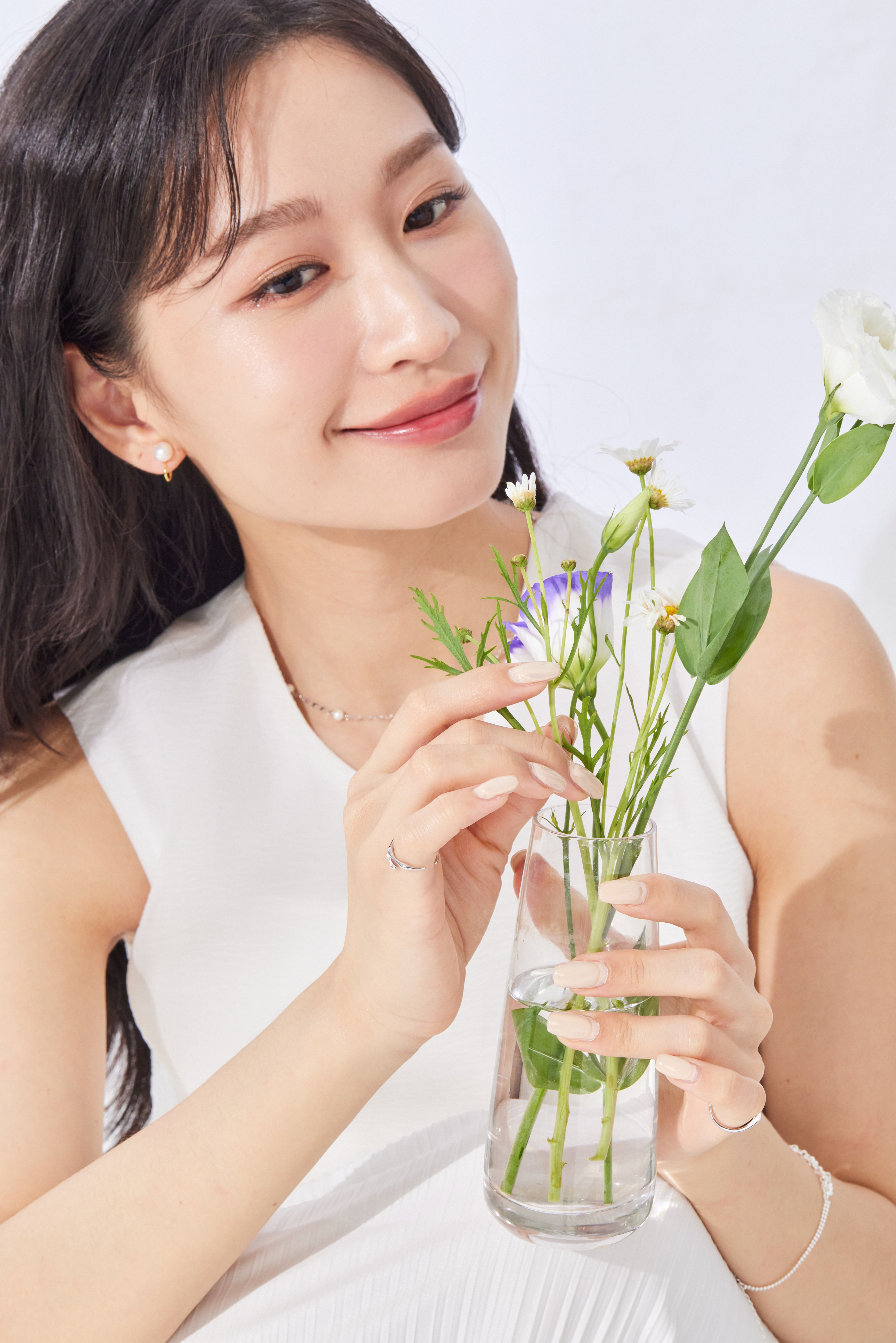模特自然摸花，尾戒低調點綴手部線條，整體造型乾淨俐落。