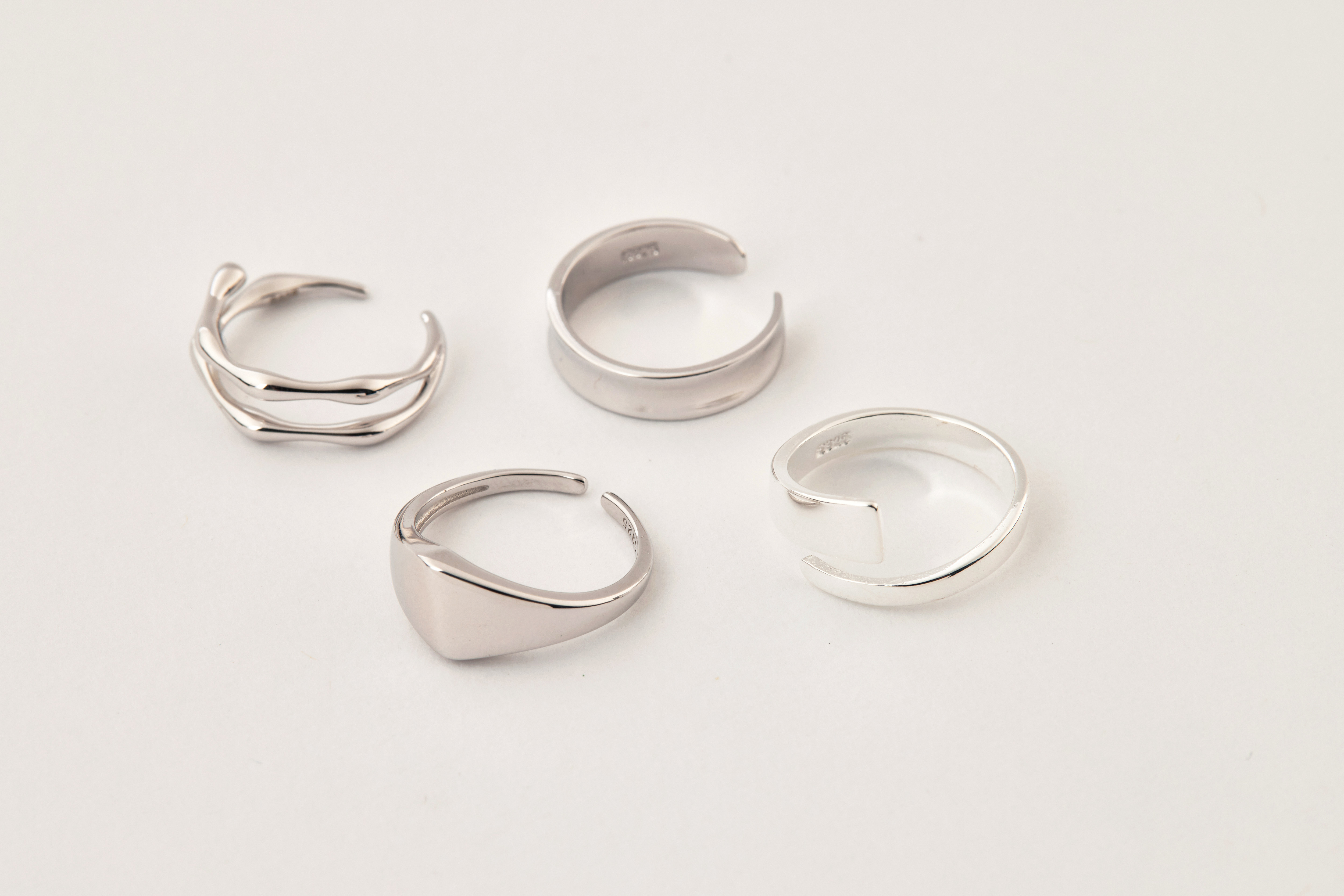 開口尾戒與三款不同風格的戒指並排擺放，呈現疊戴搭配靈感與設計多樣性。