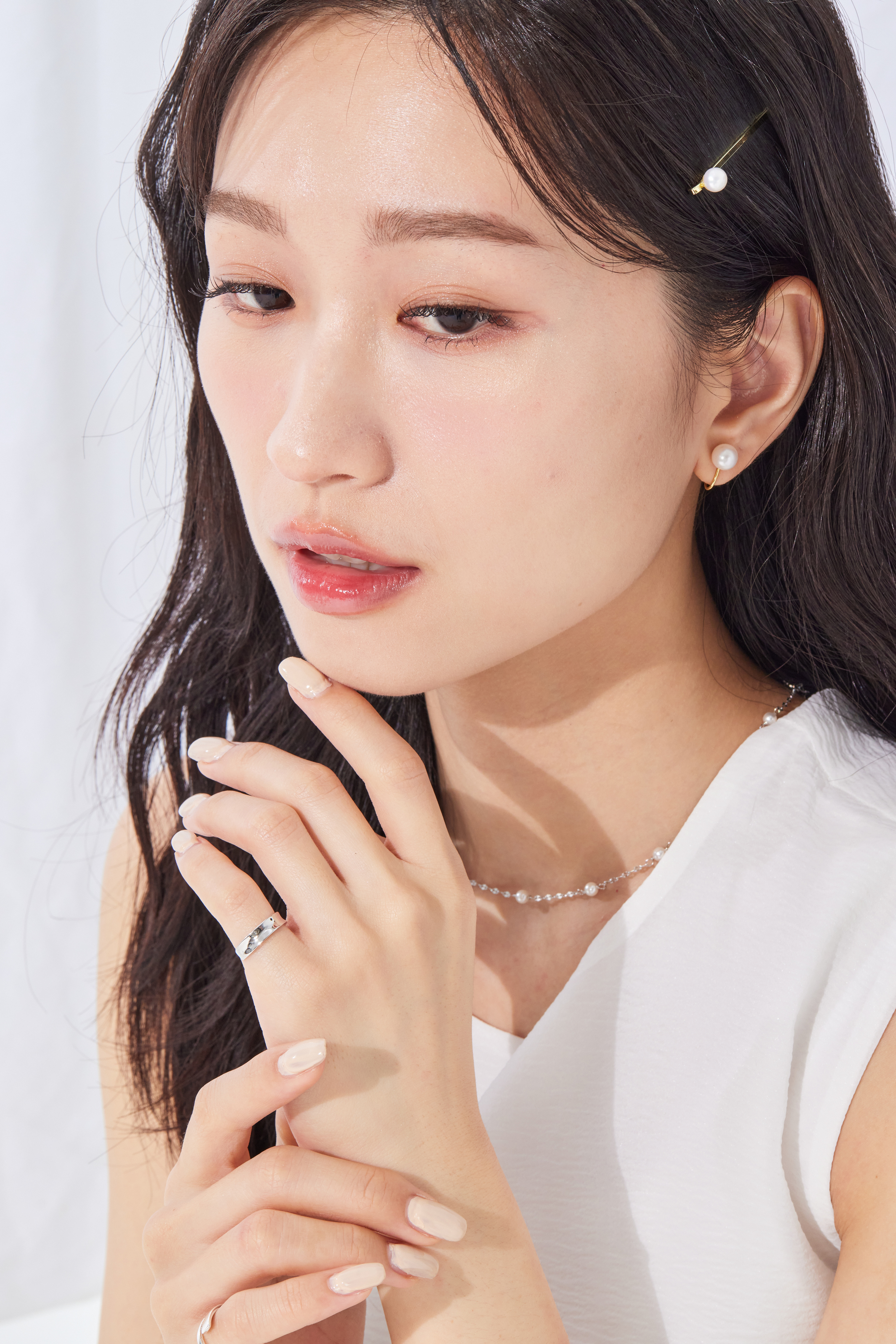 模特自然摸下巴，尾戒為整體穿搭增添低調金屬質感。