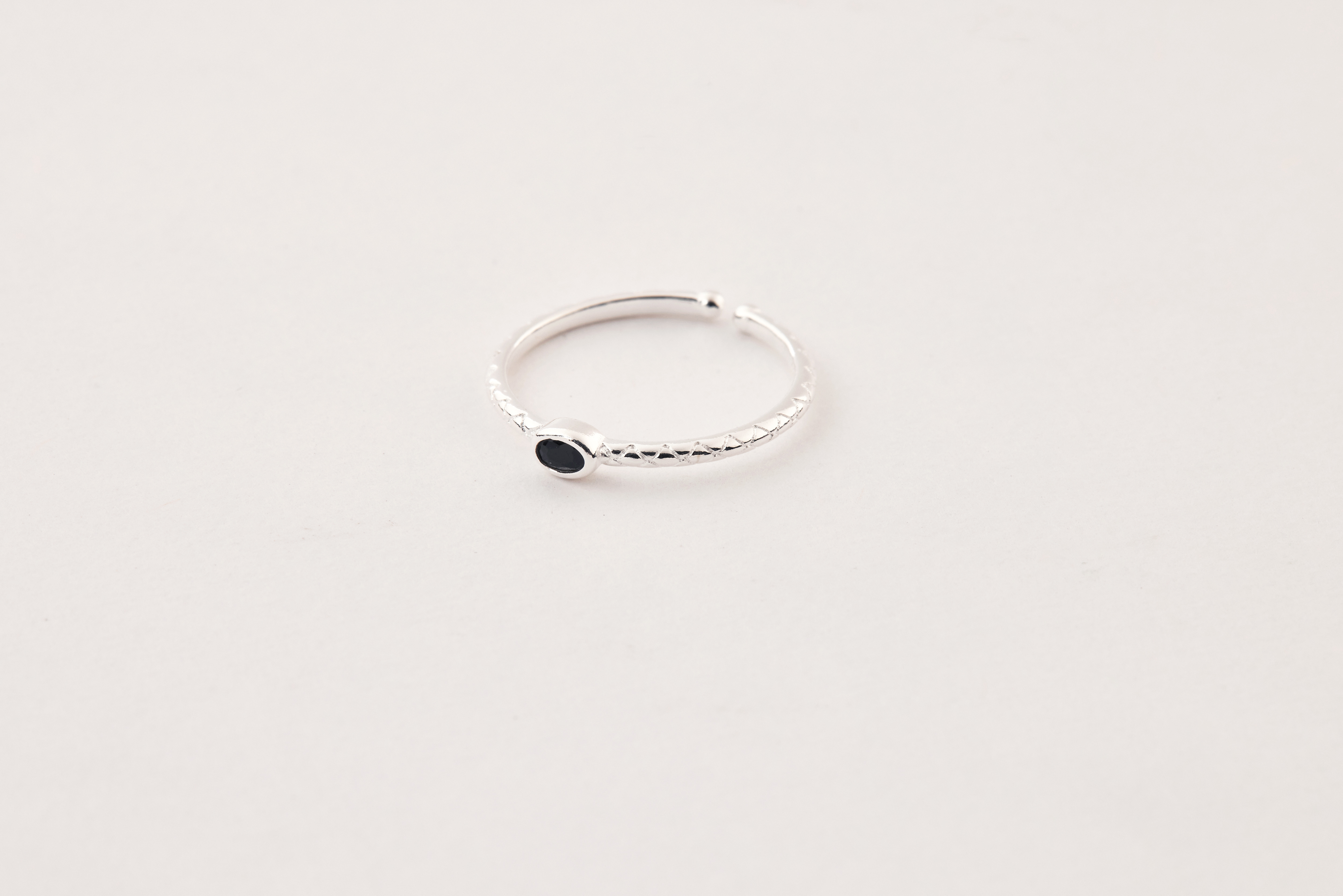 黑色鋯石戒指平放展示，簡潔戒身與神秘黑石相互映襯，氣質冷靜獨特。