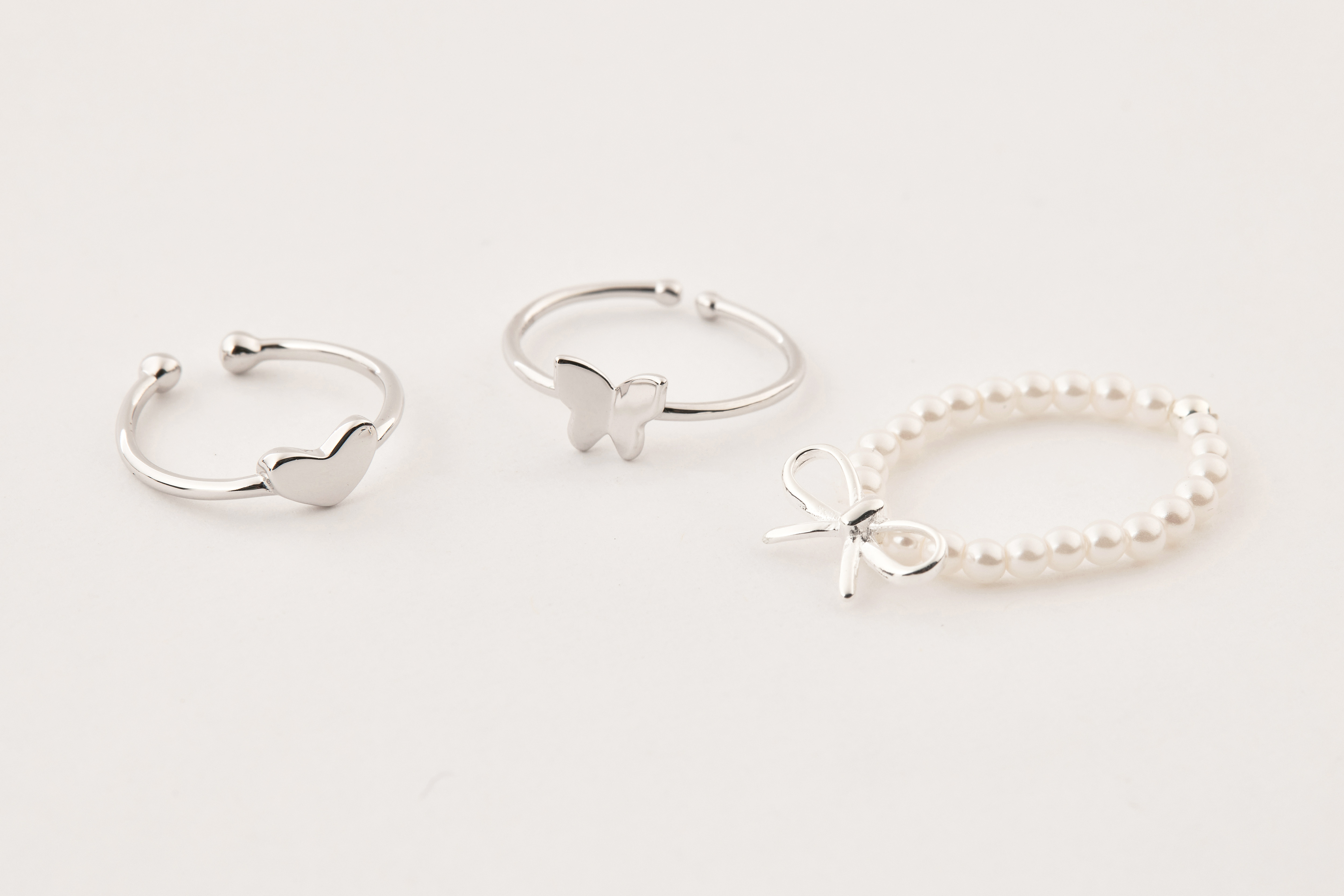 蝴蝶結珍珠戒指與另外兩款純銀戒指一同陳列，呈現多戒混搭與疊戴靈感。