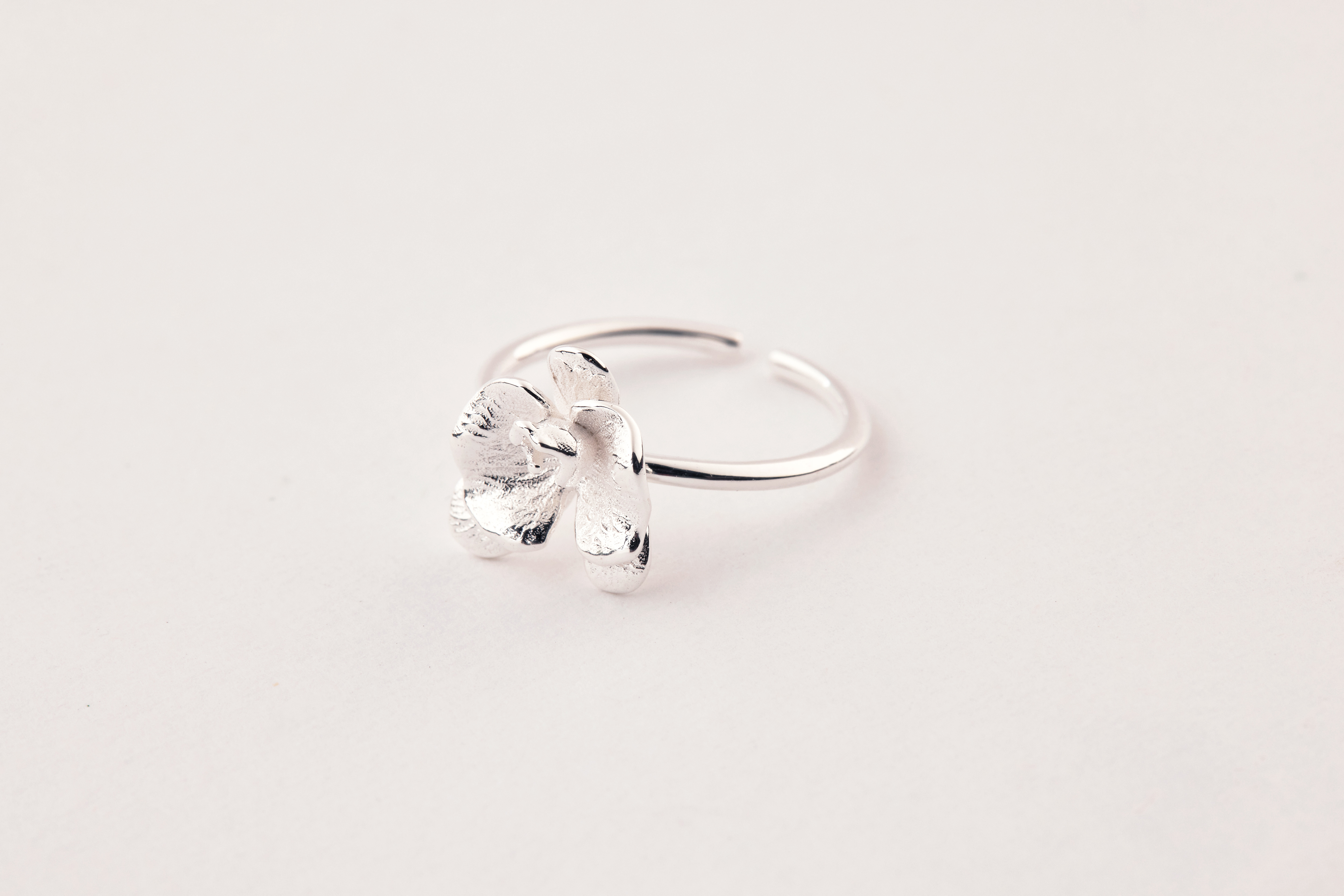 「戒指平放於淺色布面上，小花造型栩栩如生，整體質感細膩精緻。