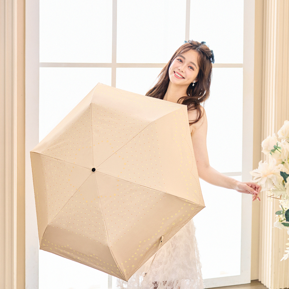 一位年輕女性拿著環保紗降溫10℃自動傘水玉_杏色站在窗戶前面