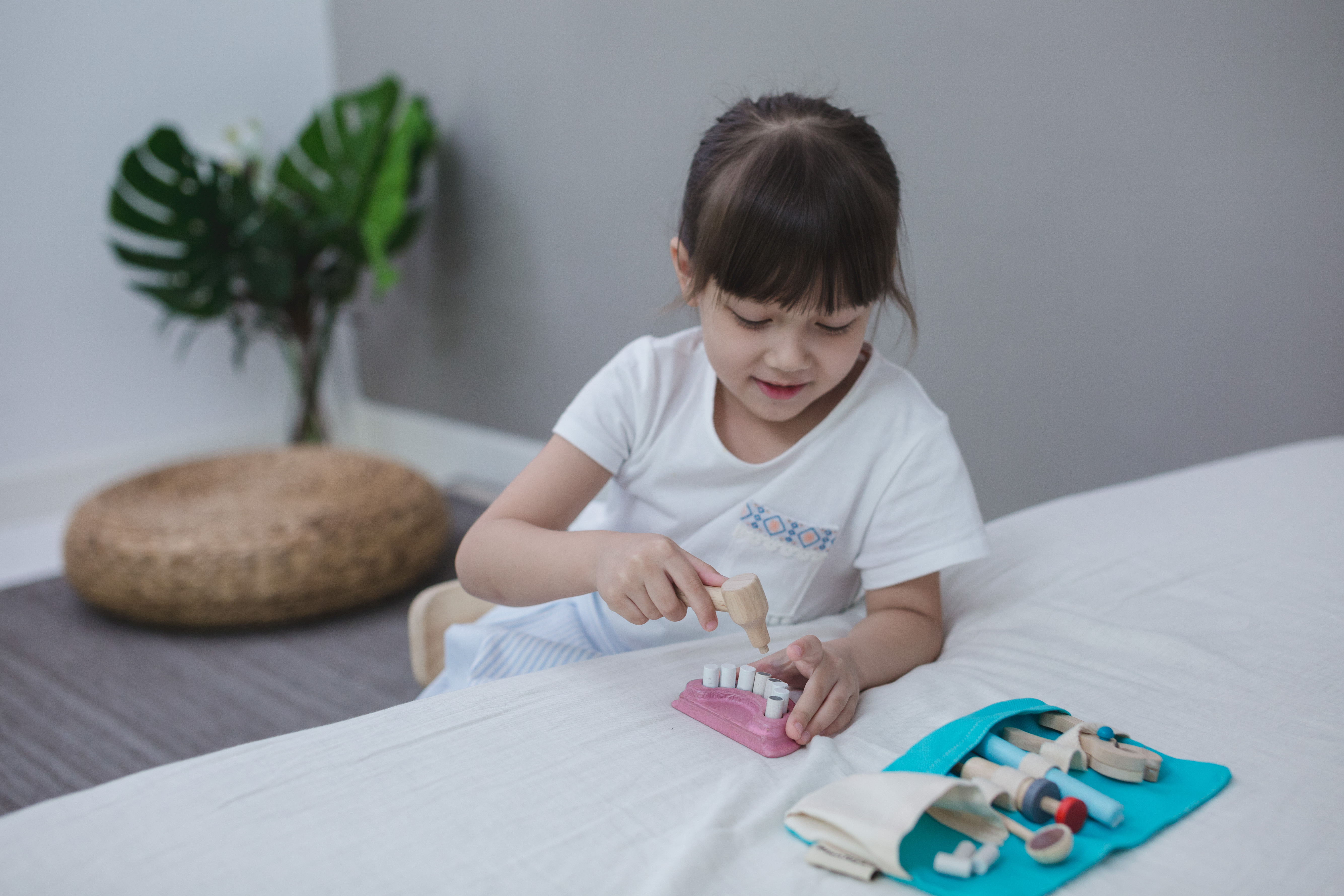 小女孩玩著 Plantoys 小牙醫木製角色扮演玩具，模擬看牙過程，訓練社交與表達能力。
