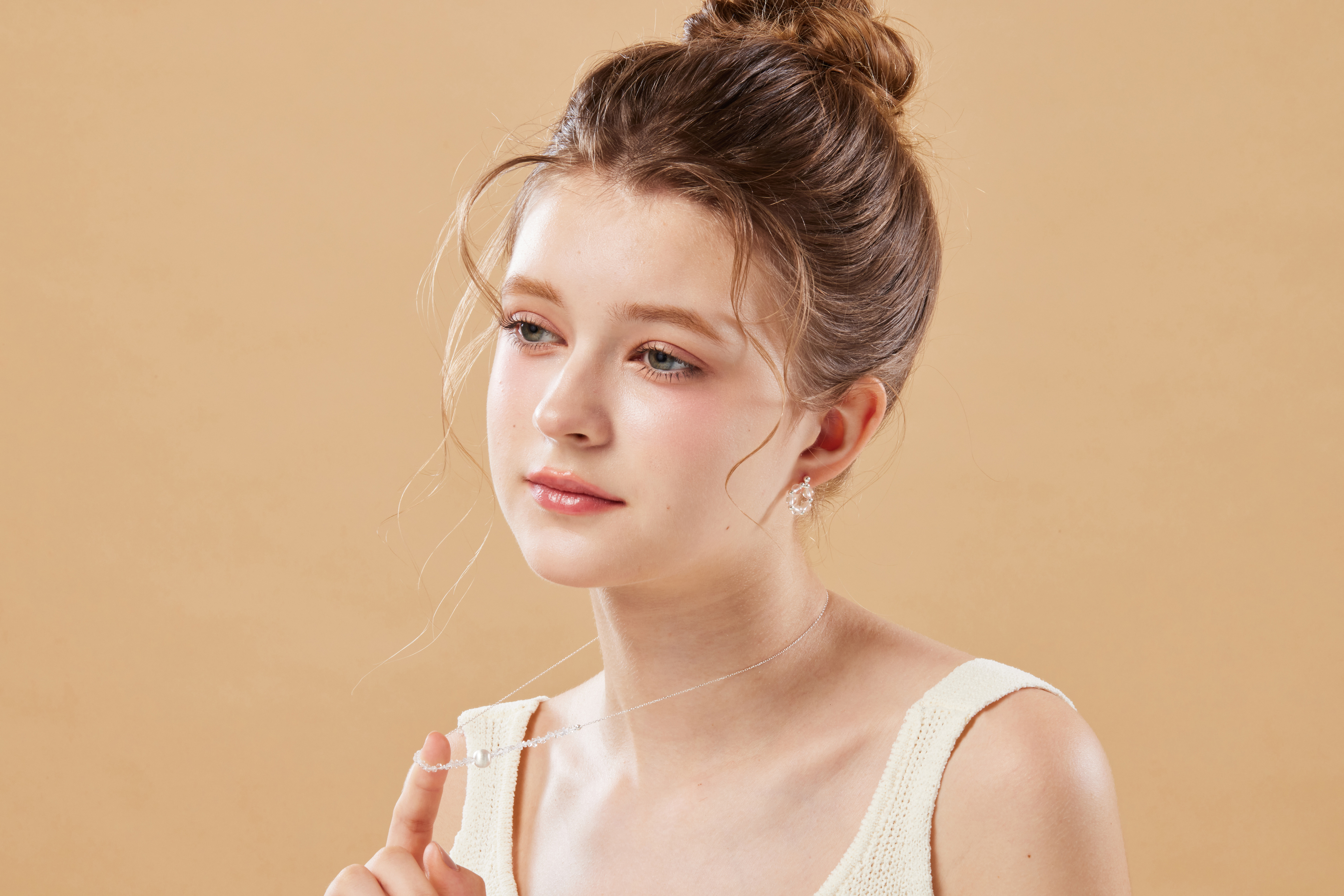 模特舉手輕撥項鍊，項鍊成為鎖骨間的溫柔點綴。