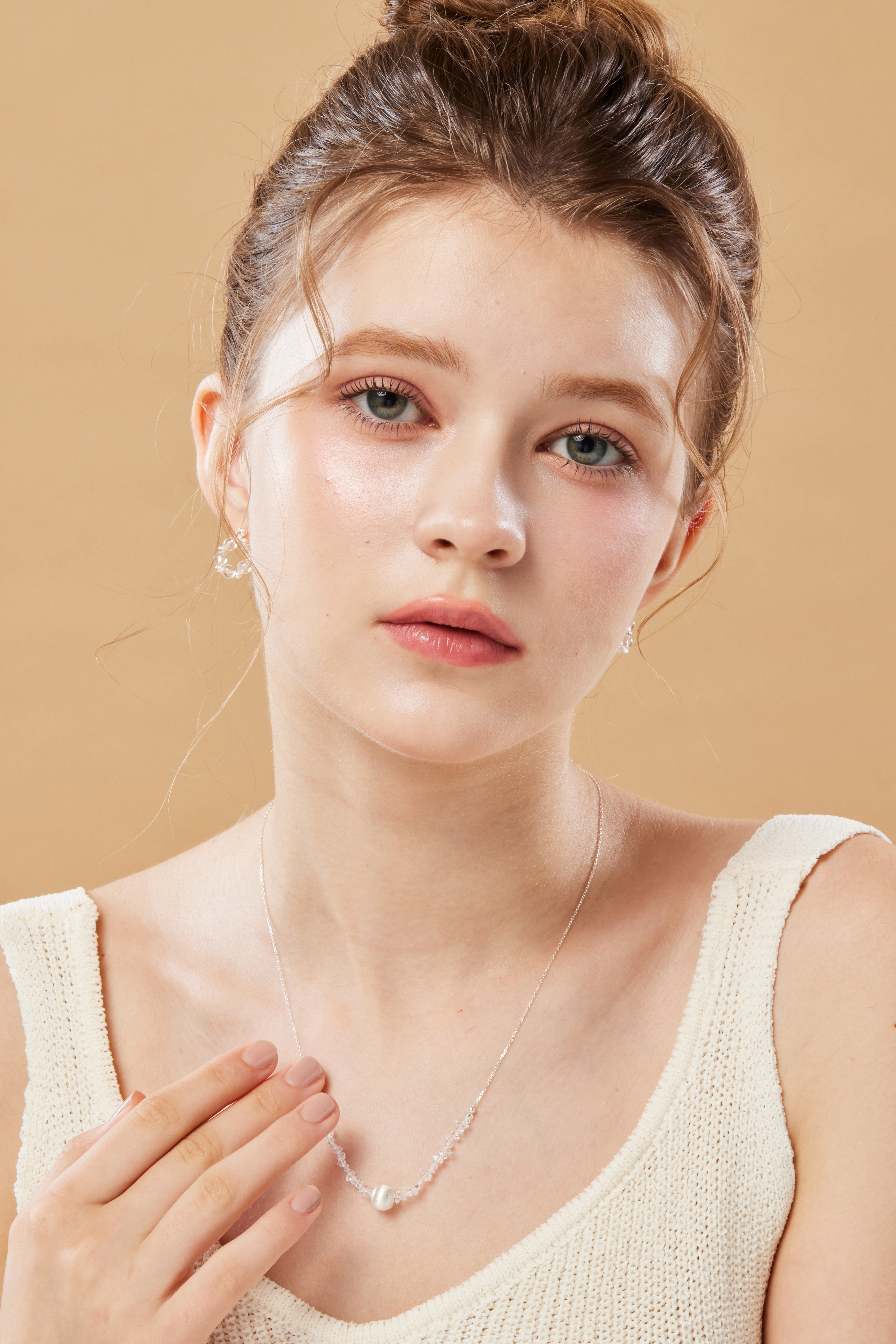 模特輕摸項鍊，貓眼項鍊隨動作微閃，畫面和諧。