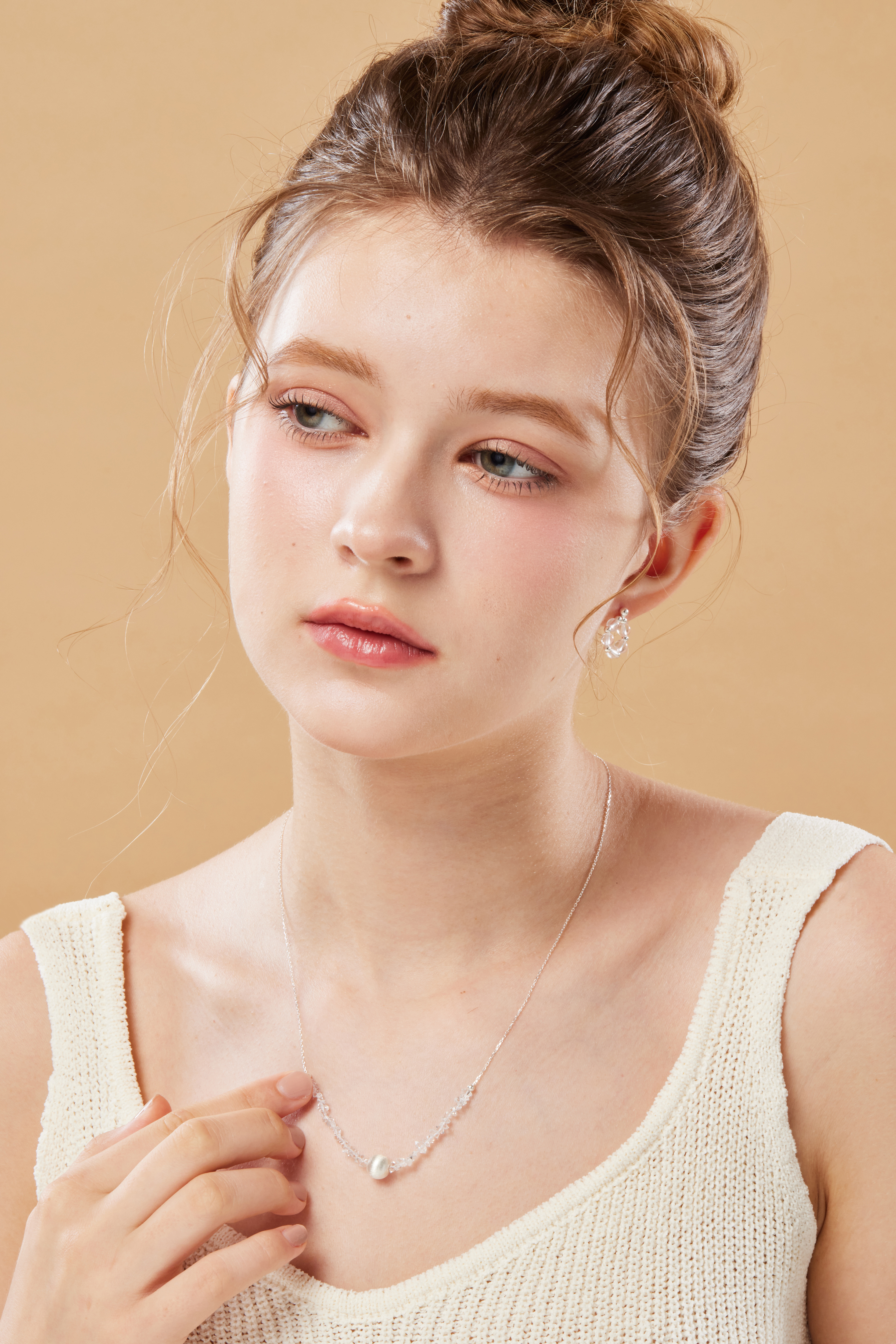 模特看向遠方，項鍊閃爍微光，畫面乾淨優雅。