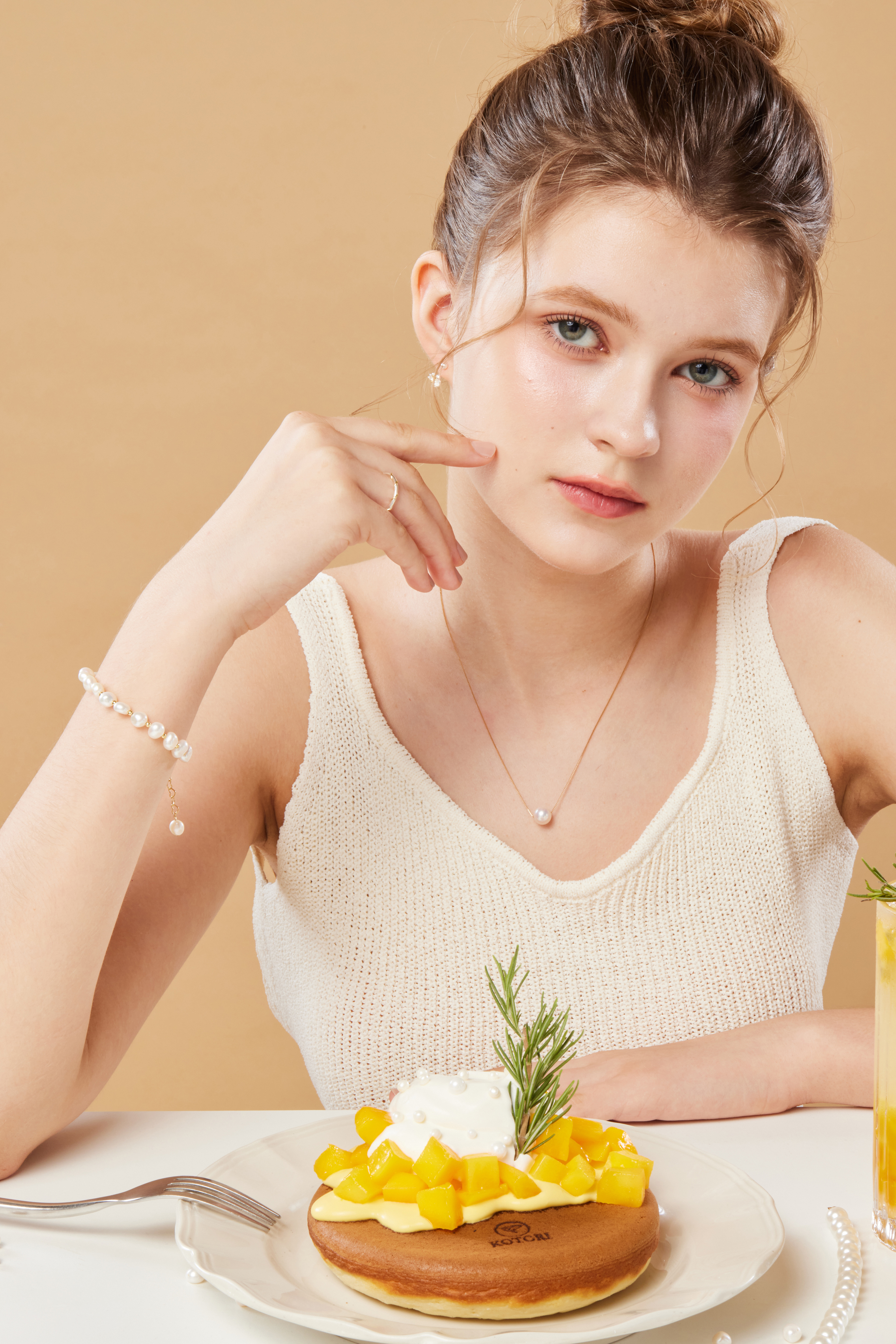 模特輕摸臉頰，手鍊於手腕輕輕閃耀，展現細節的輕盈之美。