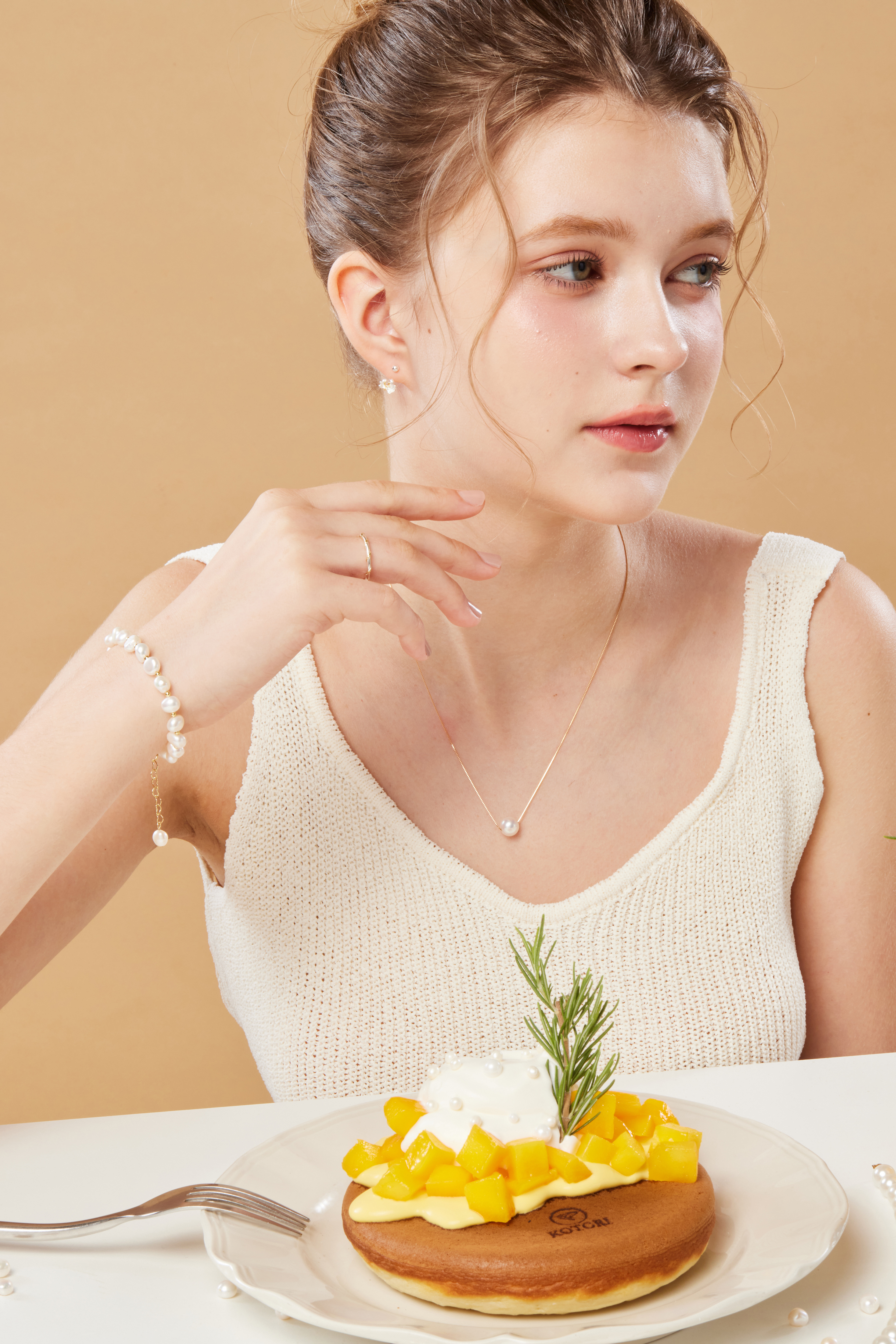 模特用甜點擺盤入鏡，手鍊與甜點共同營造柔和午後氛圍。