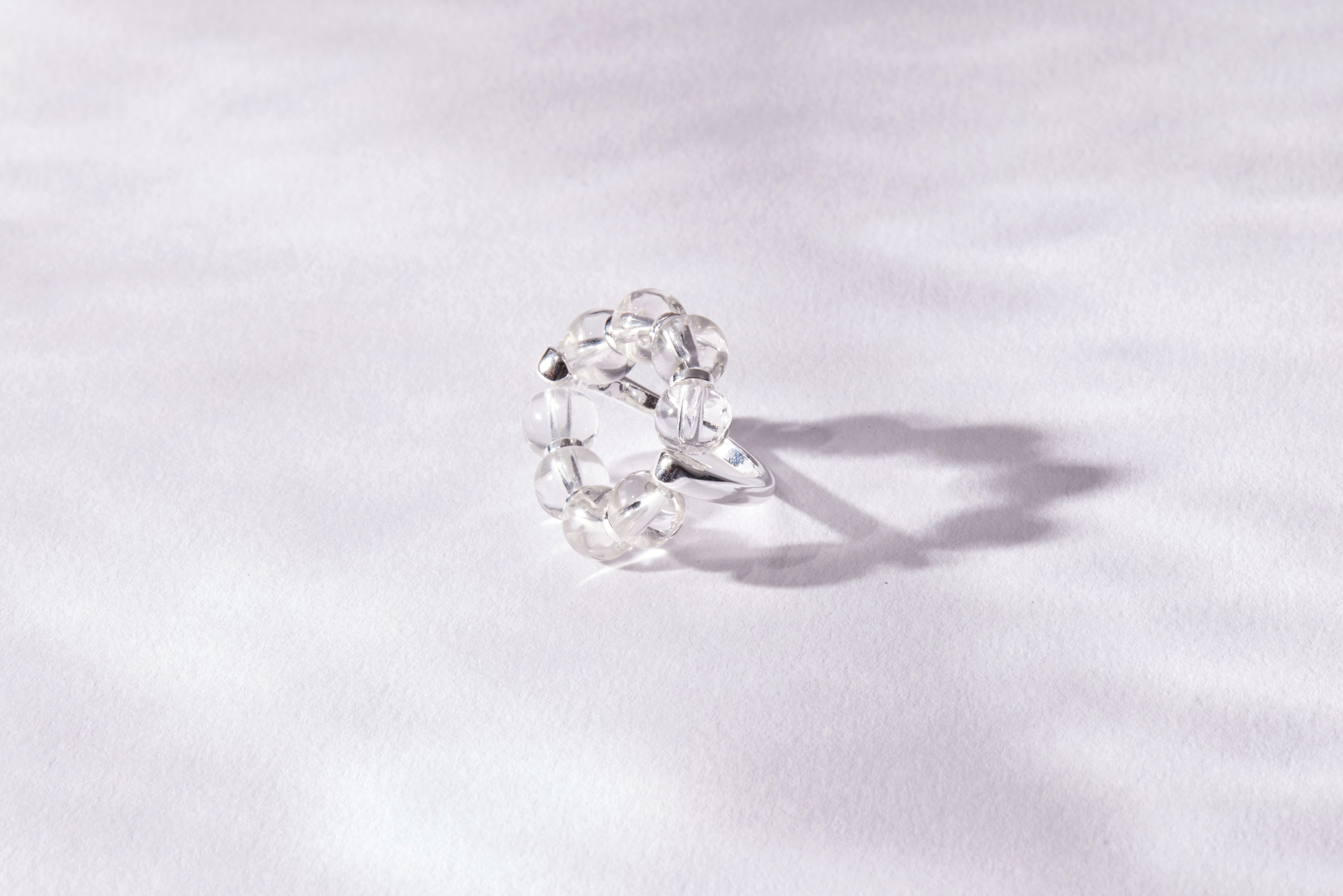 白水晶戒指平放於白色布面，光線下展現柔和透光感，細節簡練卻充滿質感。